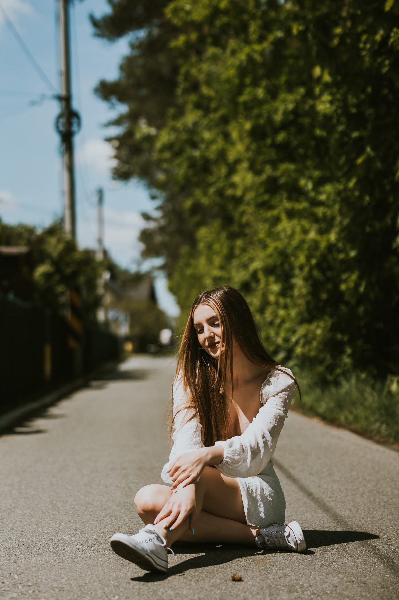 Dziewczyna siedząca na środku ulicy w białej sukience