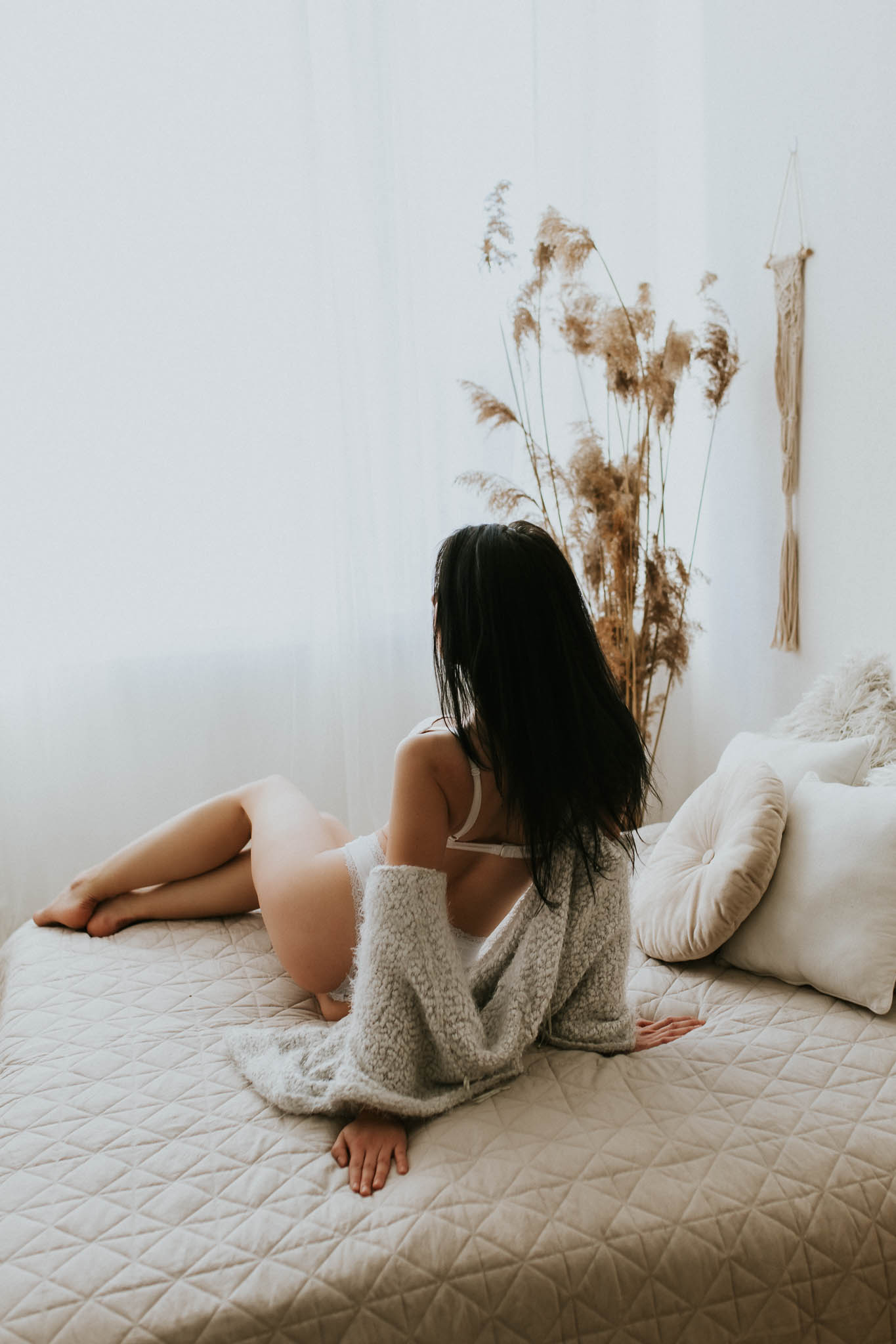 Dziewczyna siedząca na łóżku w bieliźnie i swetrze, który opada z ramion. Warsztaty sesji kobiecej