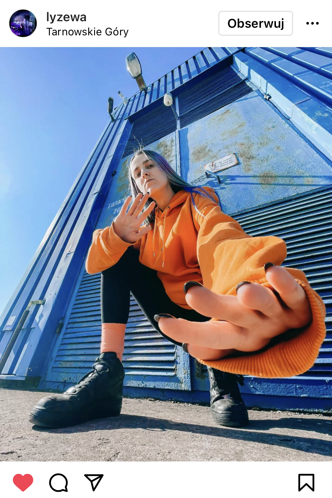 Dziewczyna w pomarańczowej kurtce kuca przed niebieskim kontenerem #śląśktakipiękny
