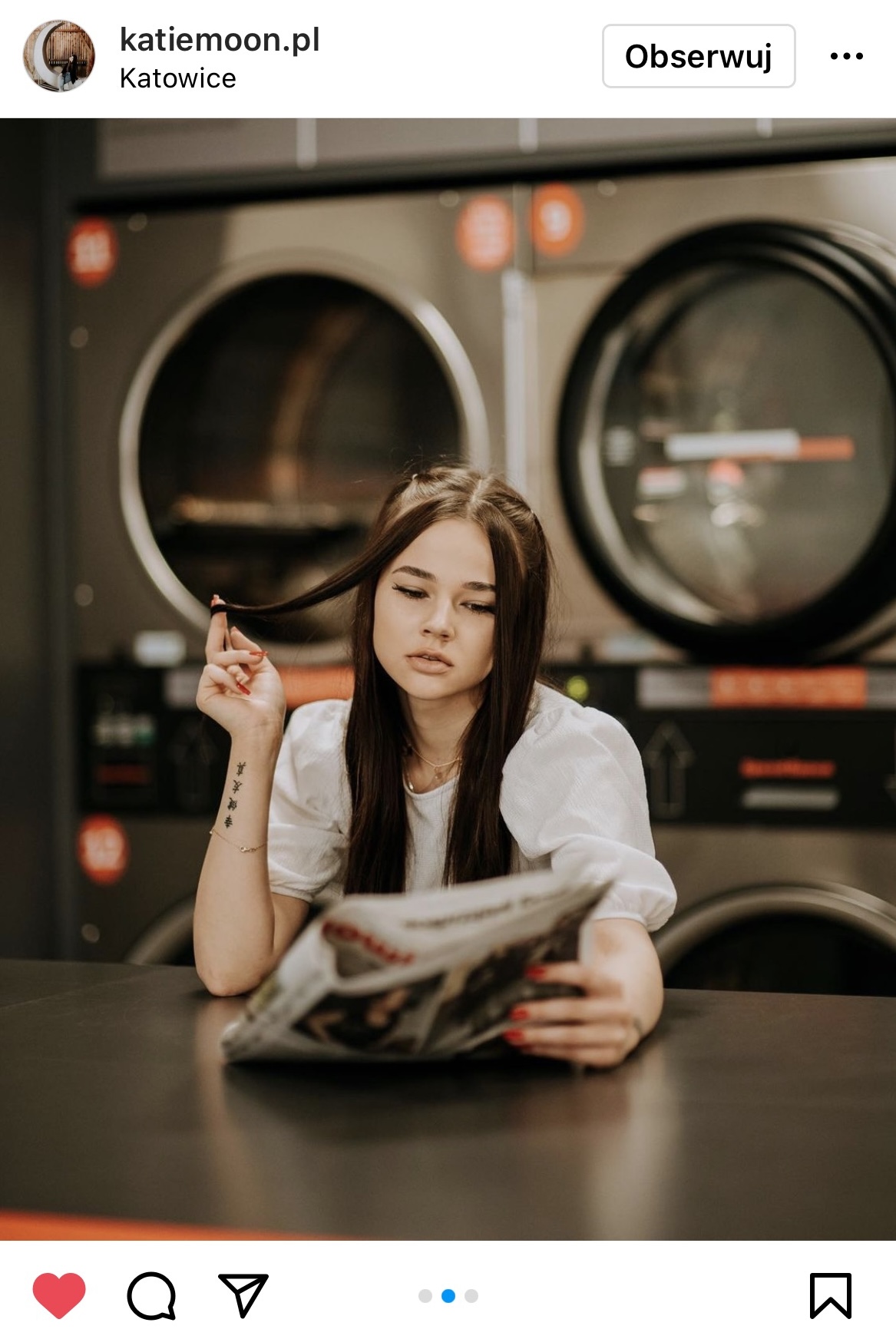 dziewczyna bawiąca się włosami i czytająca gazetę w tle pralnia