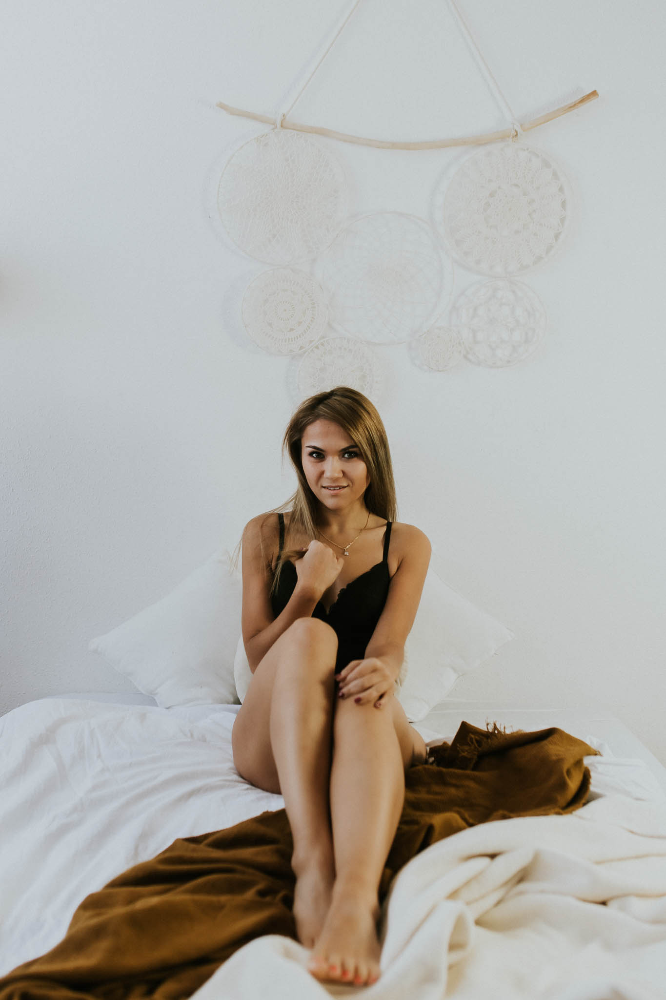 Kobieta siedząca na łóżku w czarnym body