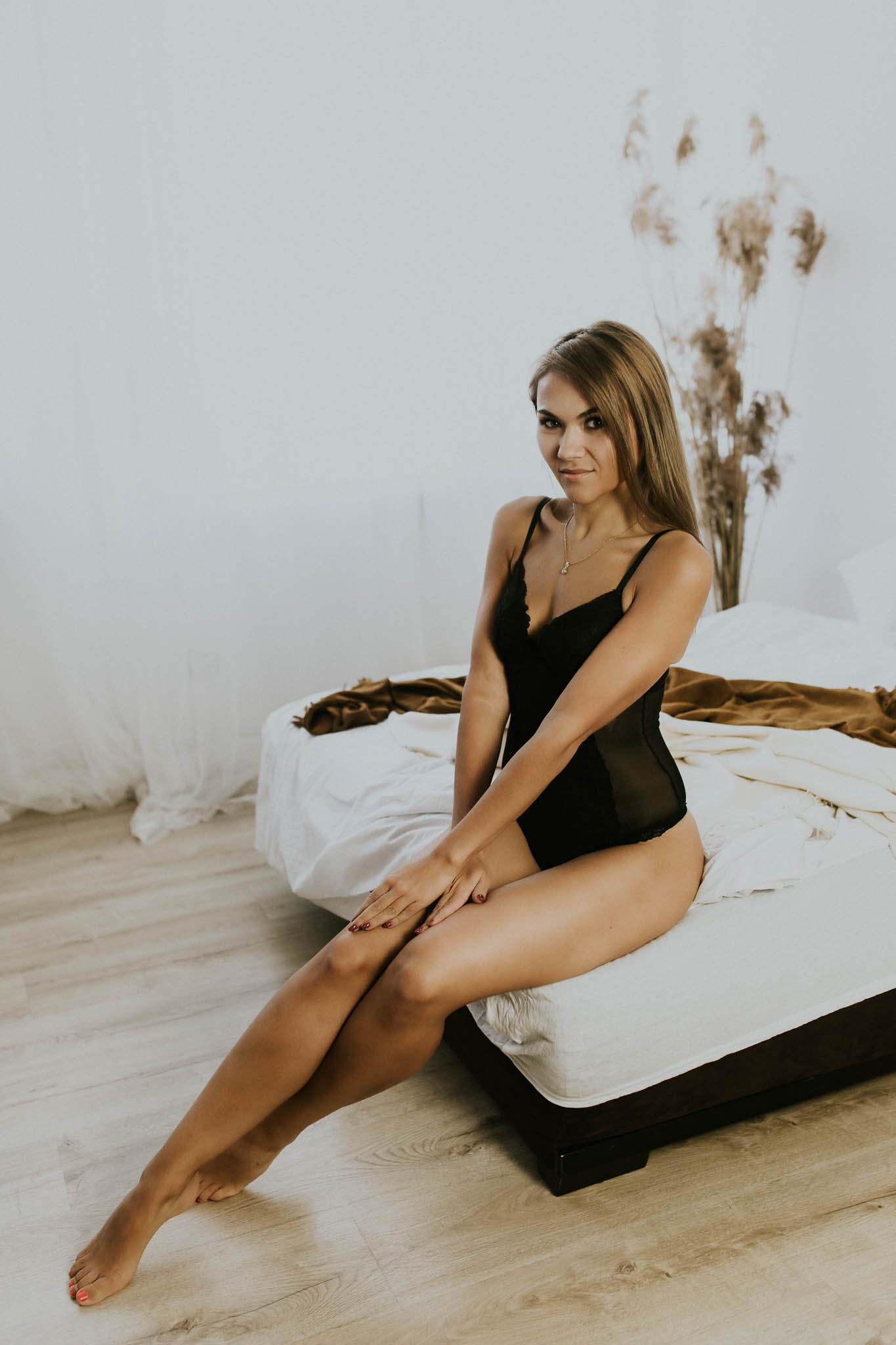 Blondynka siedząca na skraju łóżka w czarnym body