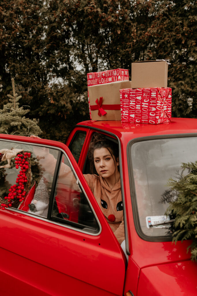 kobieta siedząca w czerwonym samochodzie na dachu są prezenty 