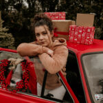 kobieta oparta o drzwi samochodu z prezentami na dachu