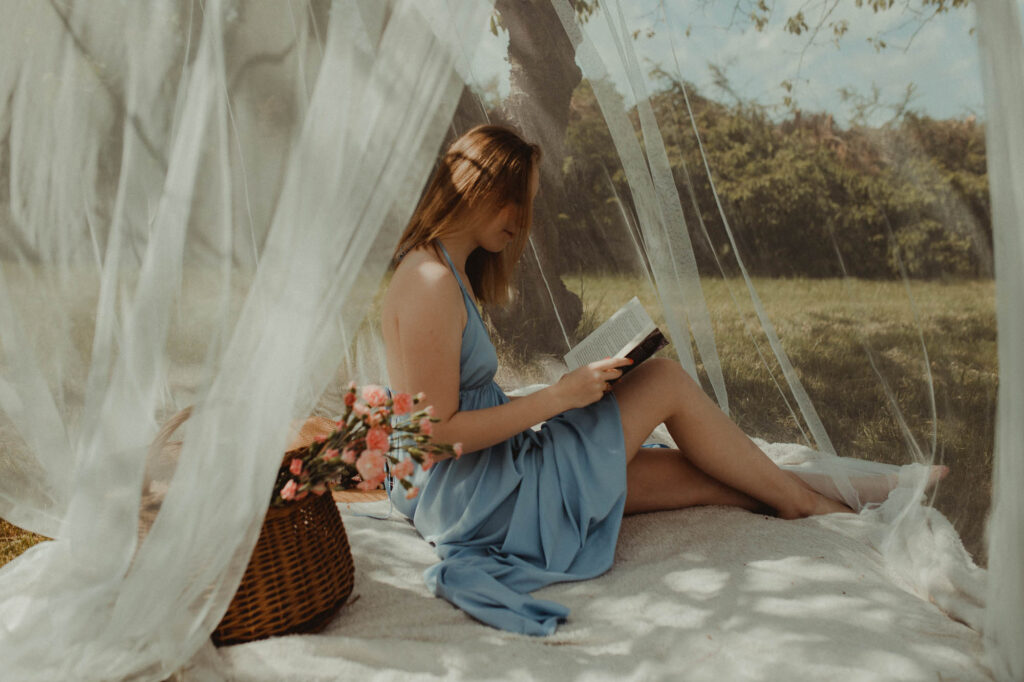 Kobieta siedzi w sielskim namiocie i czyta książkę