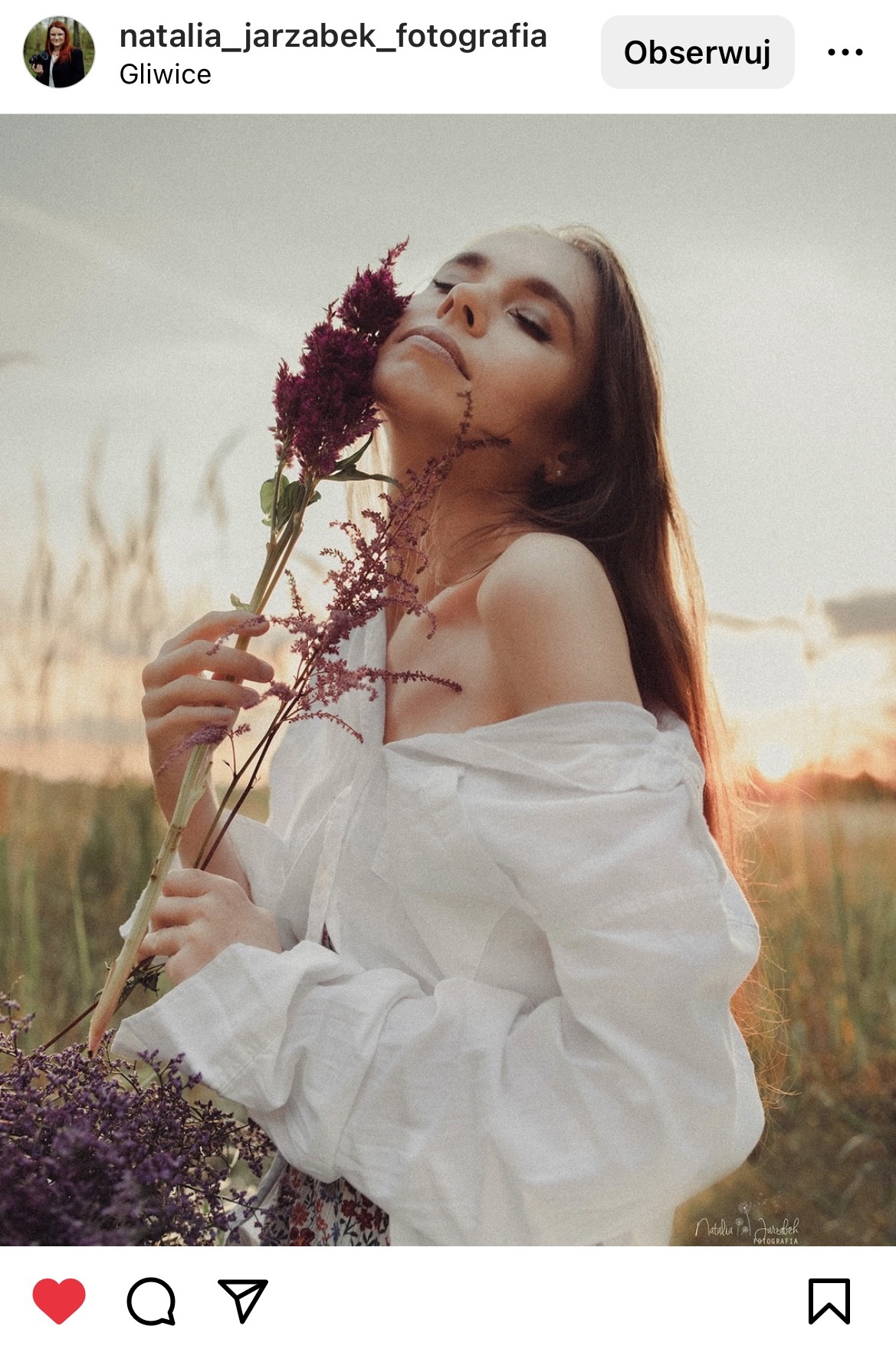 kobieta w polu ubrana w bieli, w ręce trzyma kwiat