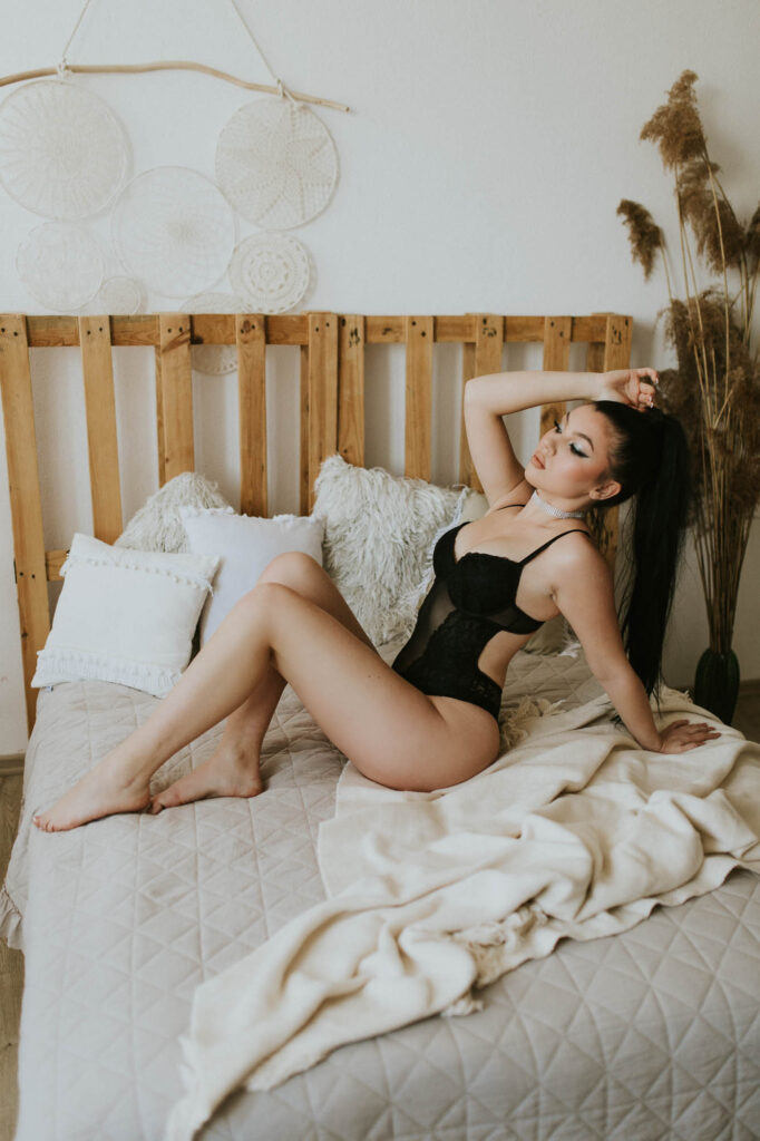 kobieta siedzi na łóżku w czarnym body
