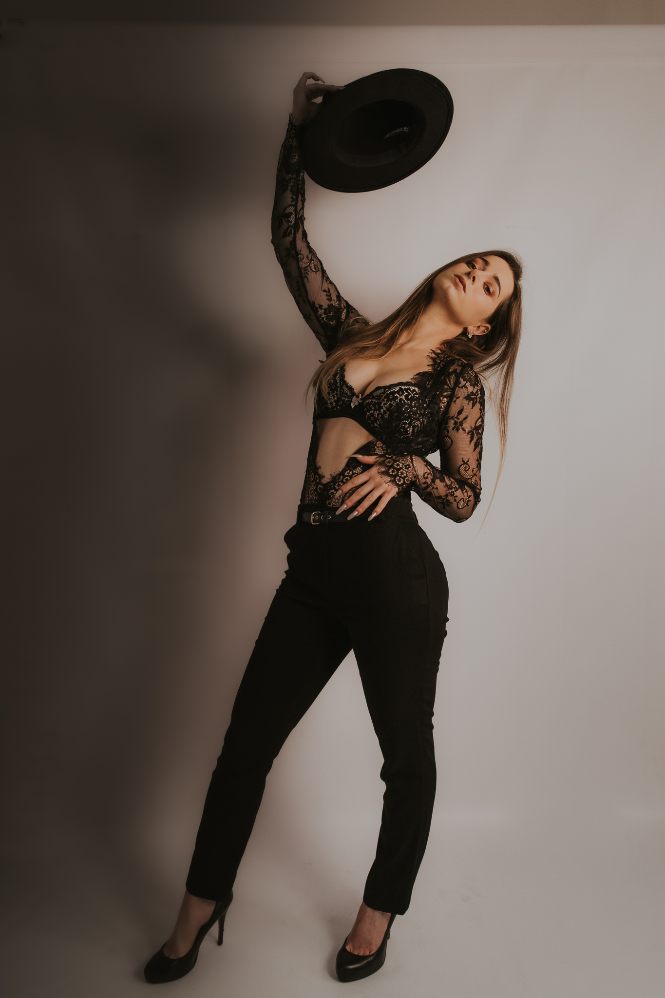 Kobieta w ręce trzymająca kapelusz, stoi przy ścianie