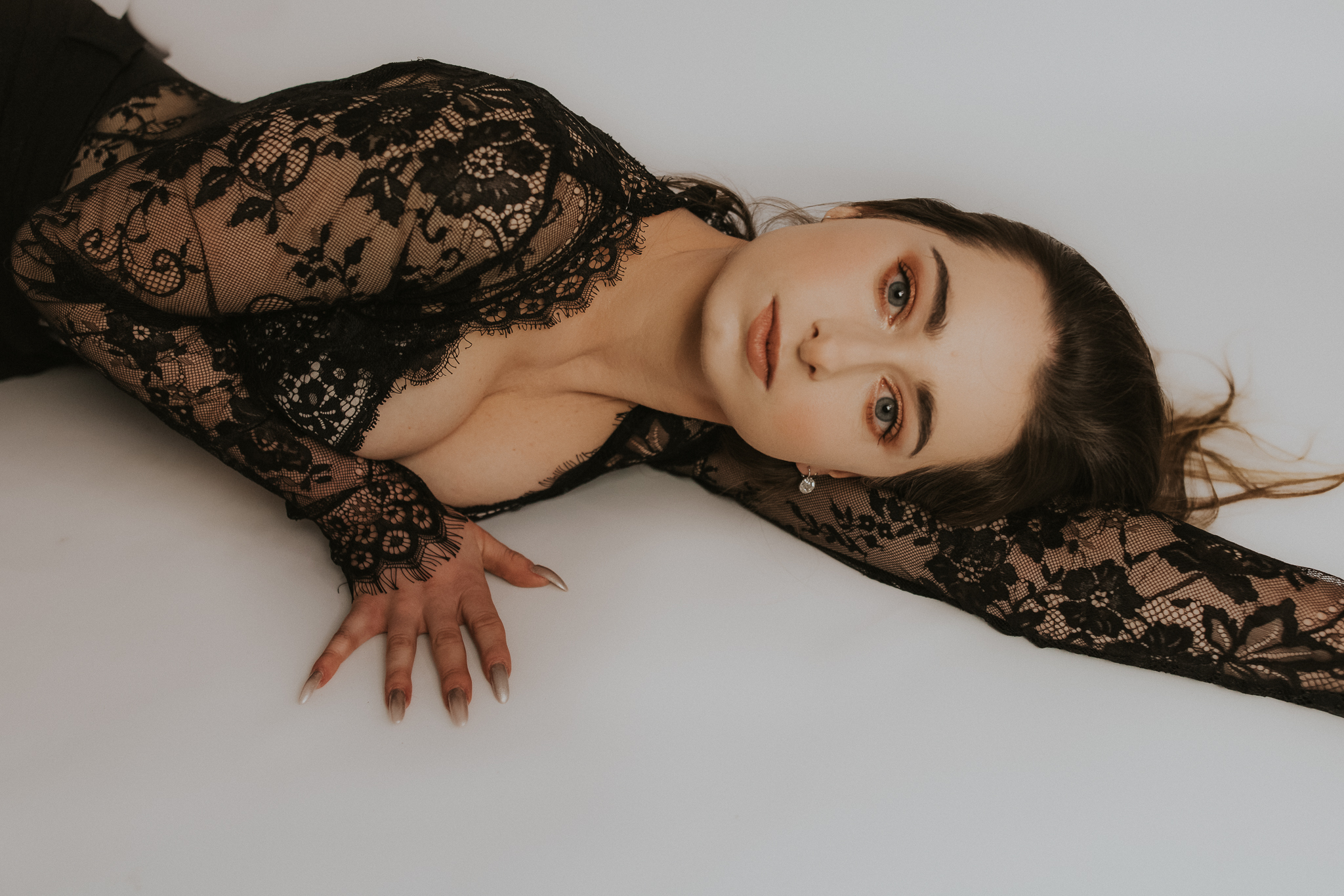 Kobieta leżąca na podłodze, twarz zakciekawiona w stronę obiektywu