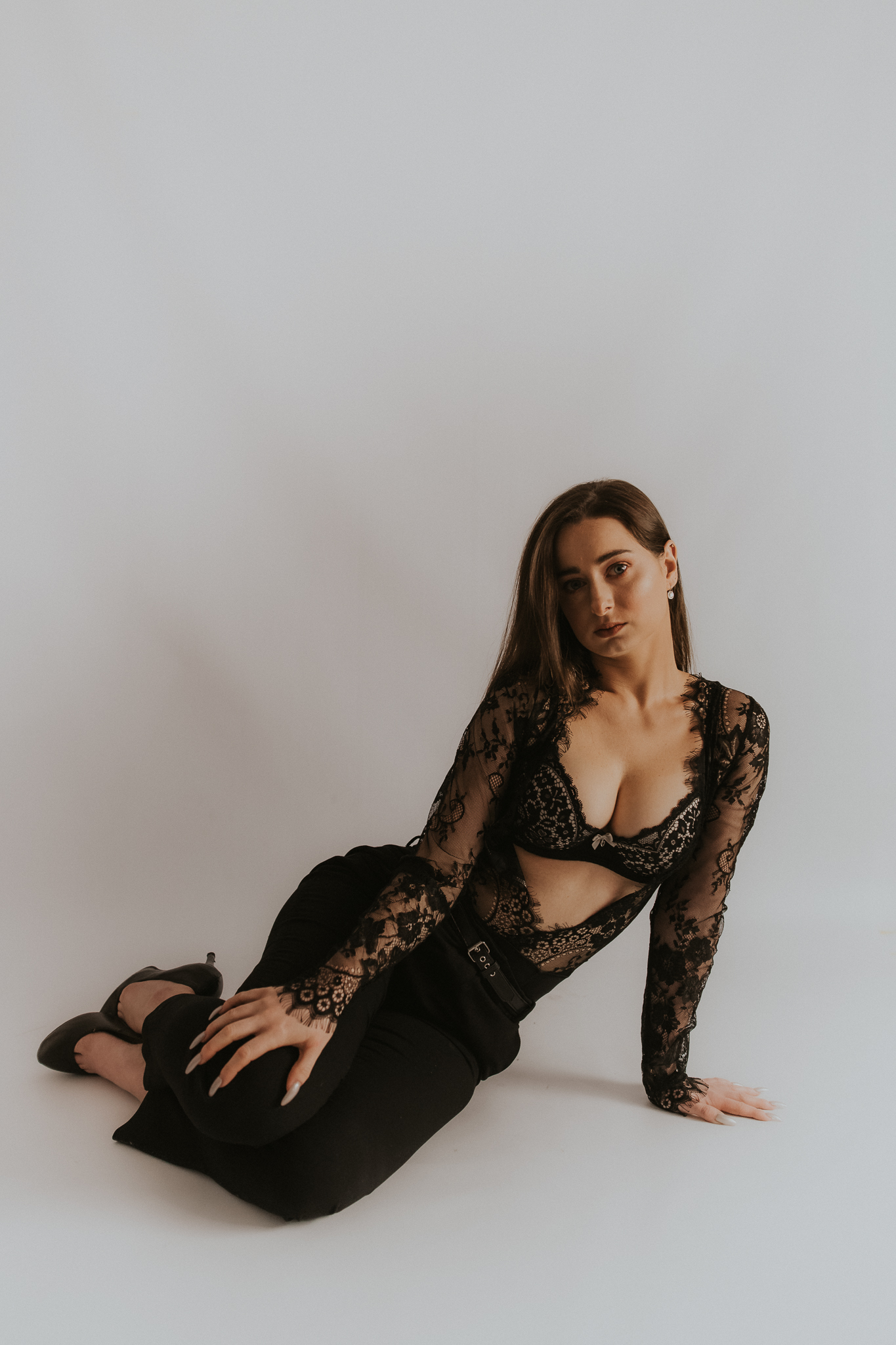 Kobieta pozująca na białym tle w czarnym seksownym ubraniu. Sesja zmysłowa