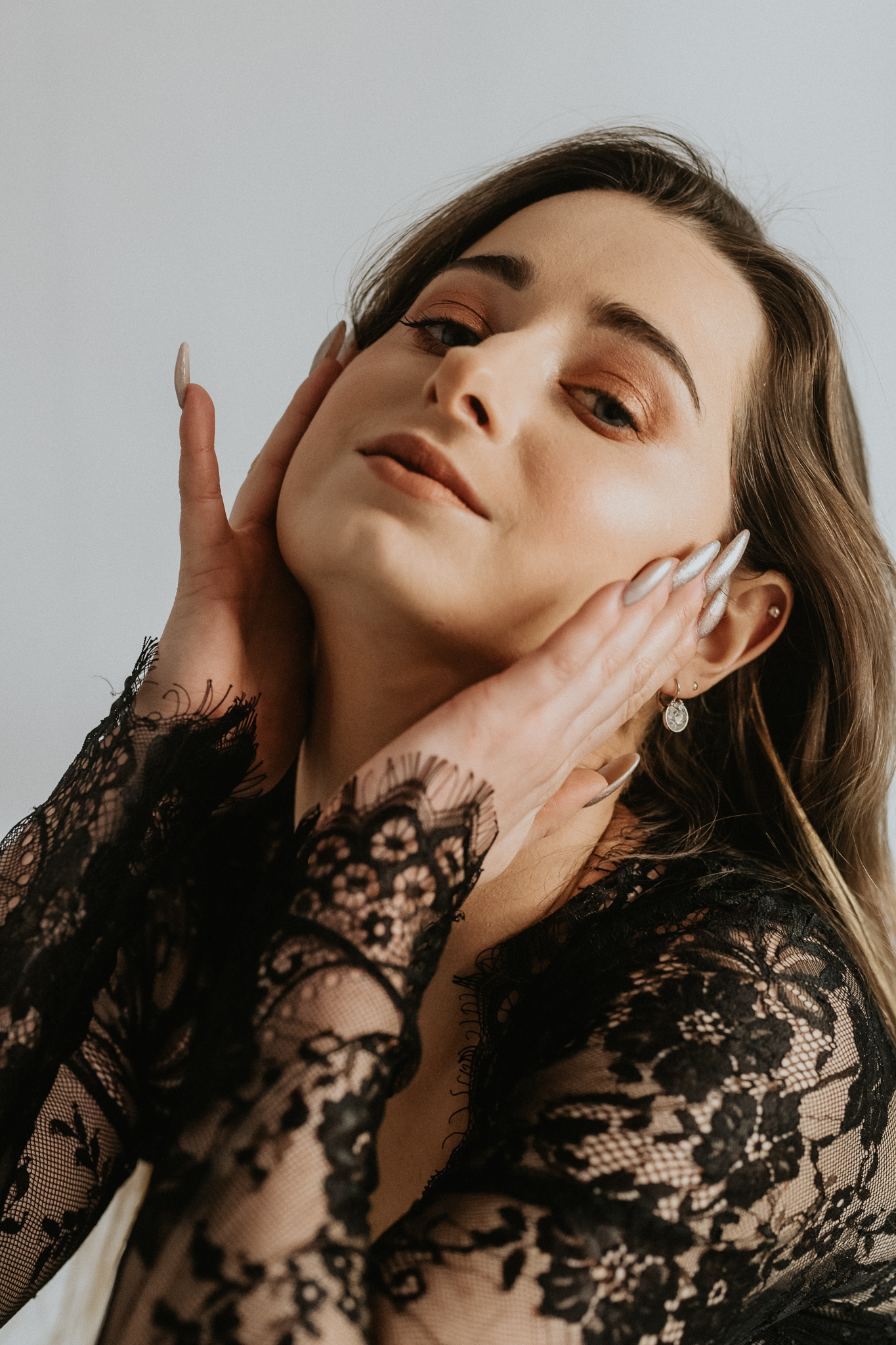 Uśmiechnięta kobieca twarz, dłonie ma na skroniach