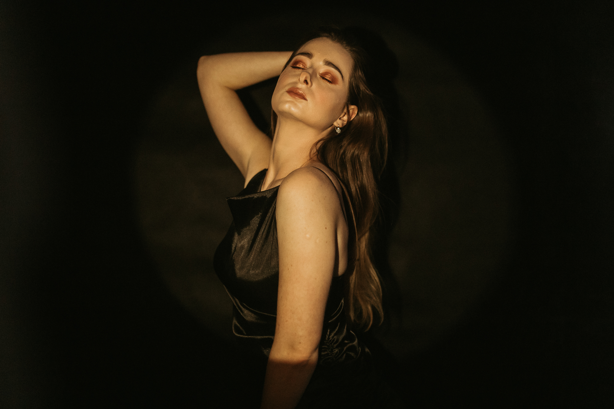 Dziewczyna ma zamknięte oczy i jedną ręką trzyma się za głowę. Pozuje. Sesja zmysłowa