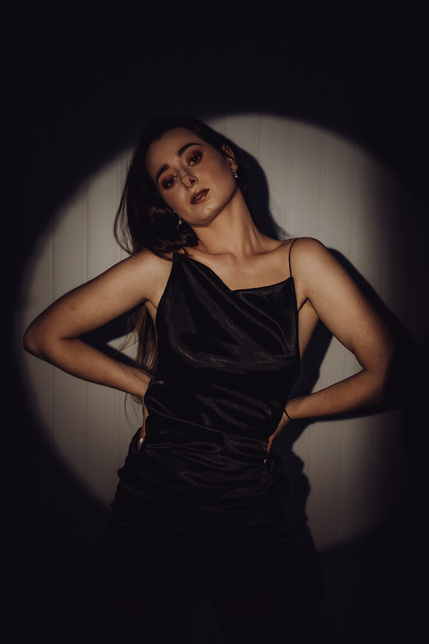 Dziewczyna z rękami w talii spogląda w obiektyw ze skrzywioną głową