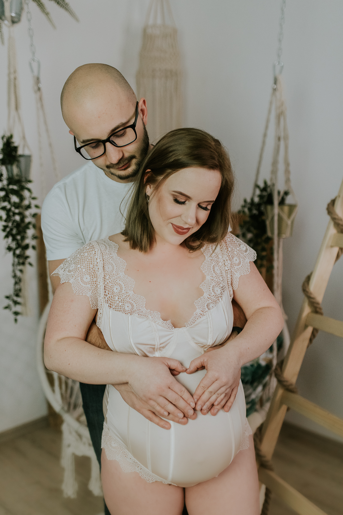 Mężczyzna obejmuje kobietę i trzyma ją za brzuch. Uśmiechają się