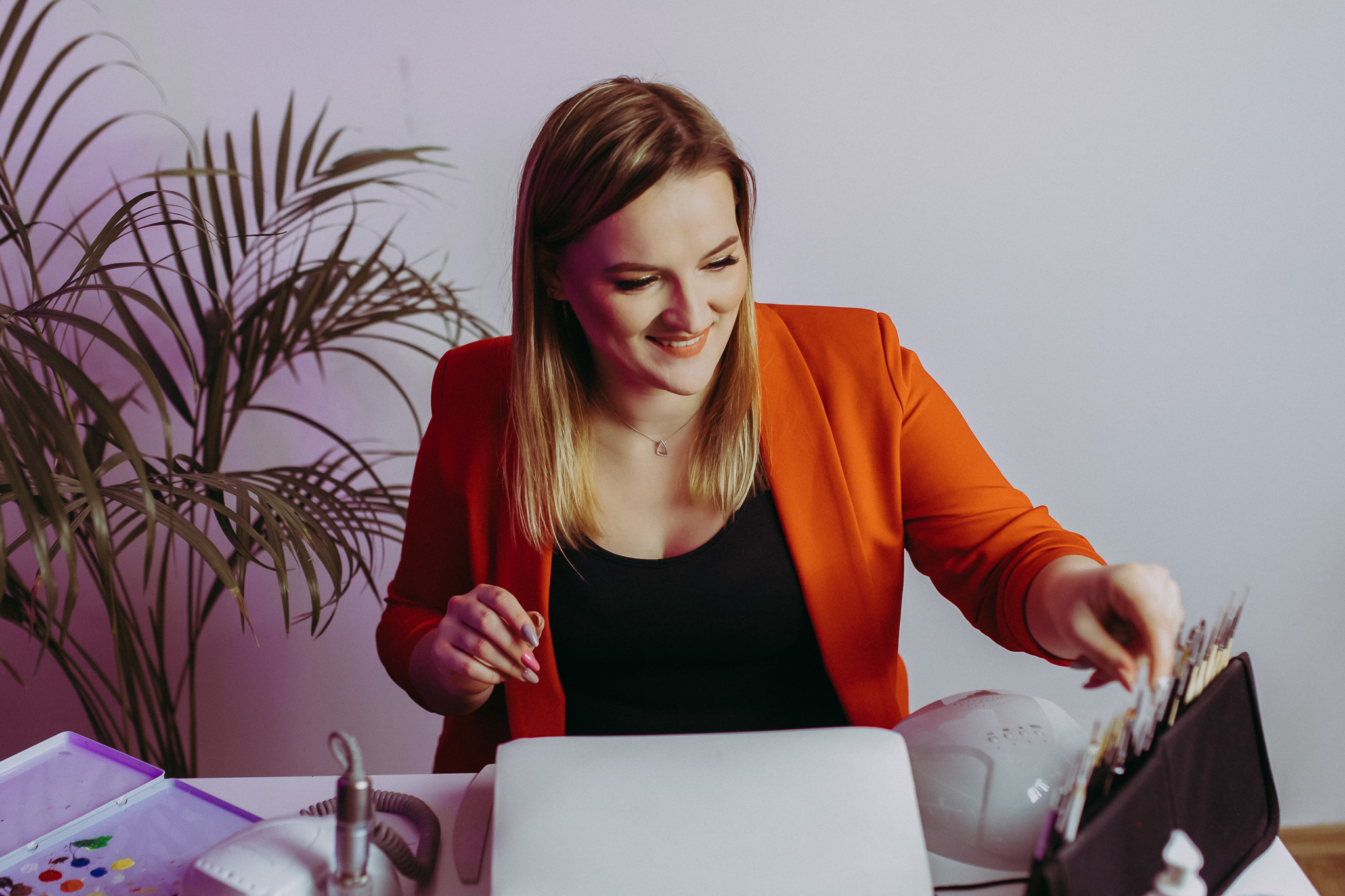 Uśmiechnięta pani odkłada coś na bok biurka.