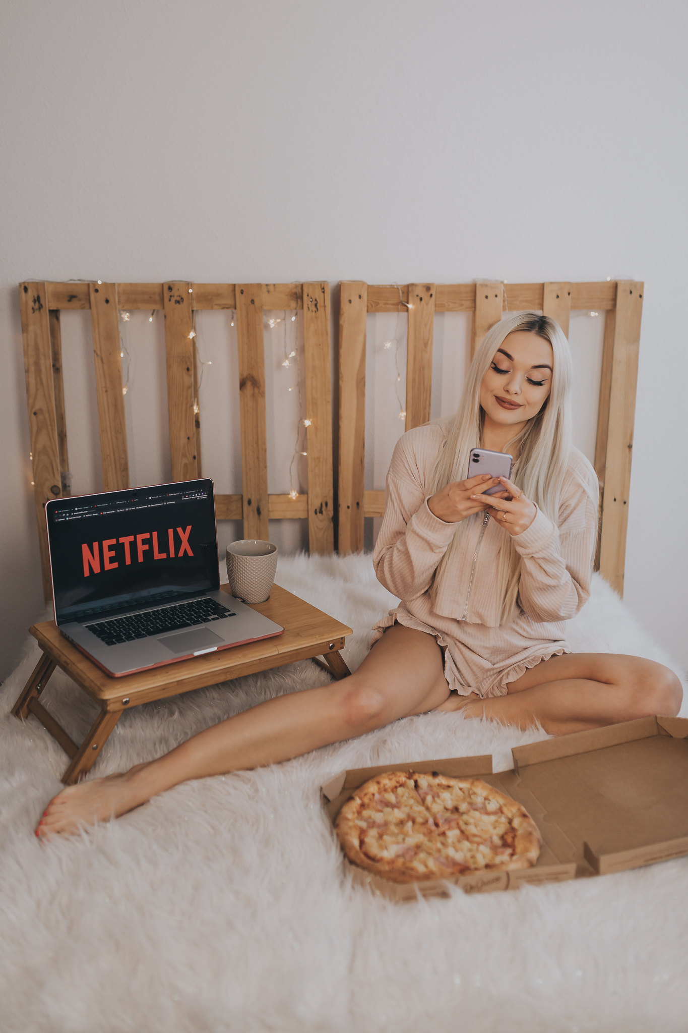 Dziewczyna siedzi na łóżku z pizzą i laptopem