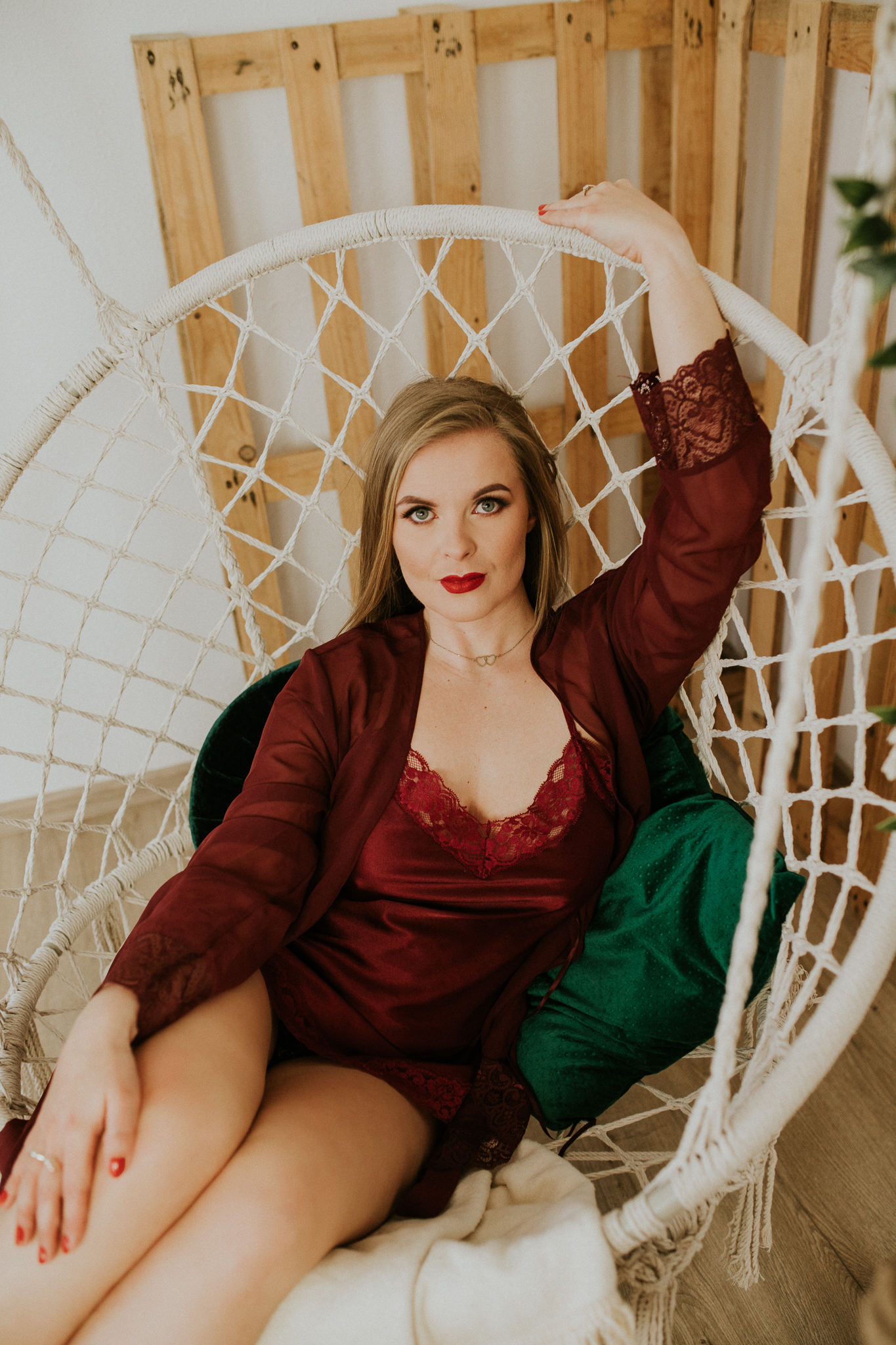 Kobieta siedząca na okrągłej, plecionej, białej, wiszącej hustawce