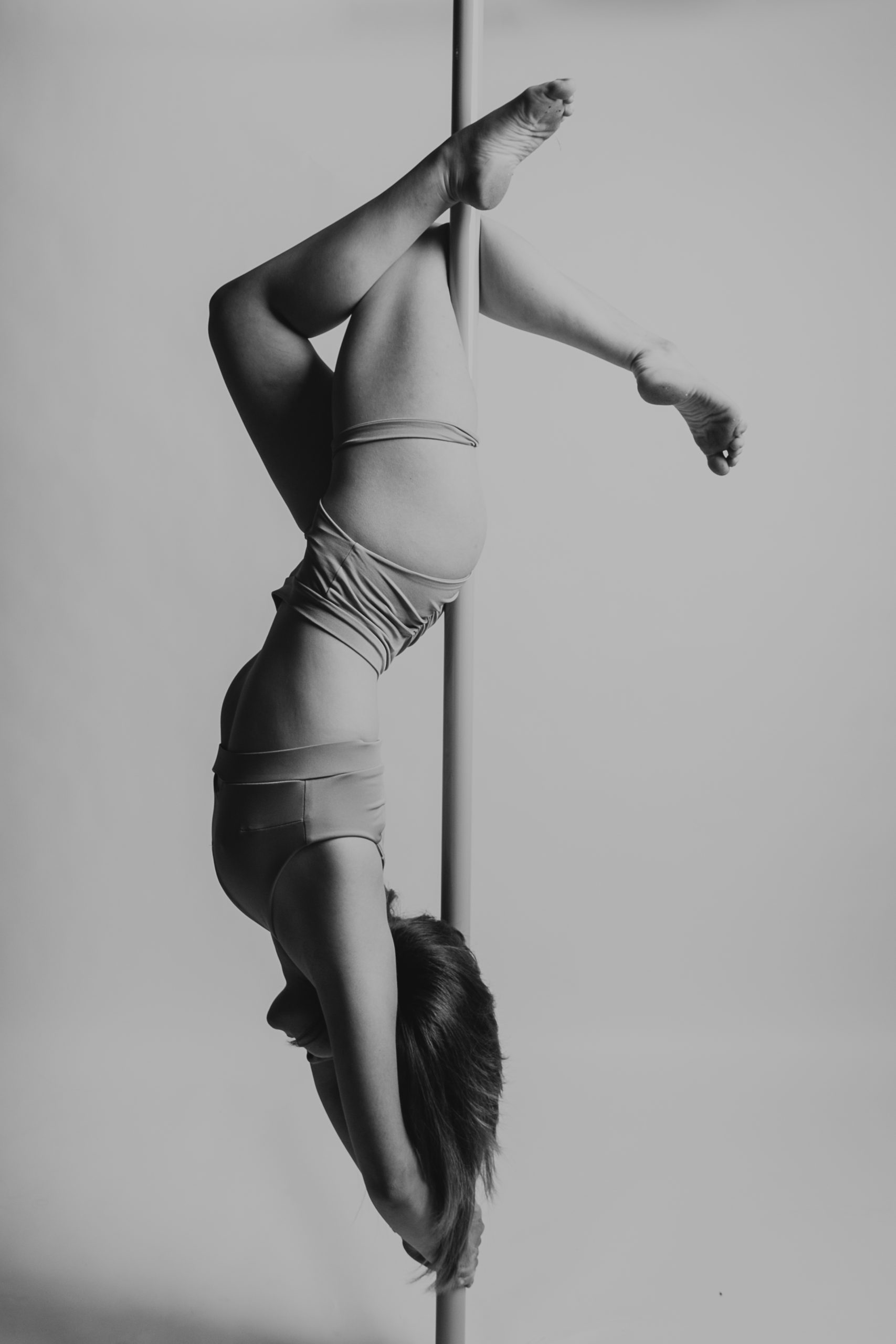 Kobieta owinięta o rurę pole dance z głową w dół
