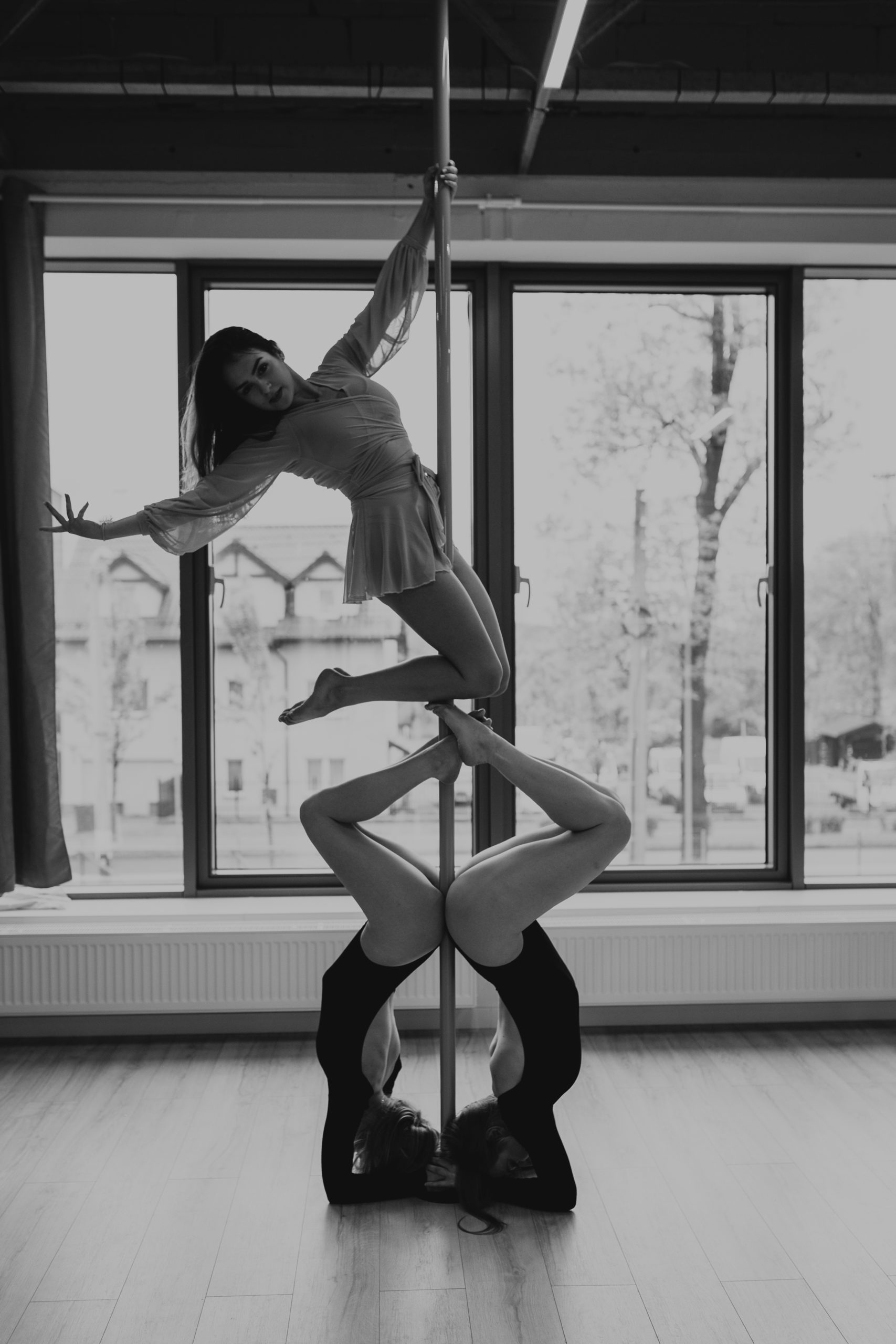 Trzy dziewczyny robiące figury na rurze pole dance wspólnie