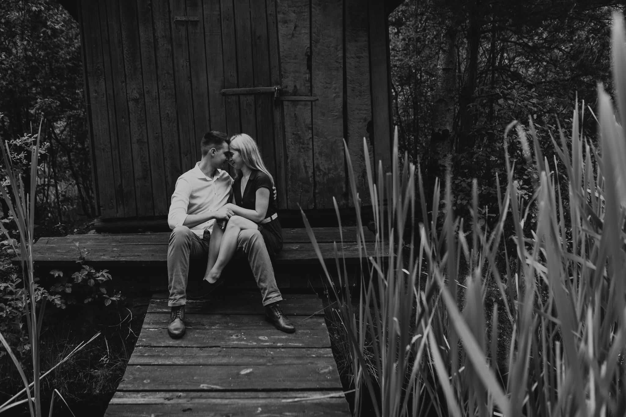 Czarno- białe ujęcie pary, która siedzi na wejściu do domku i patrzy sobie głęboko w oczy