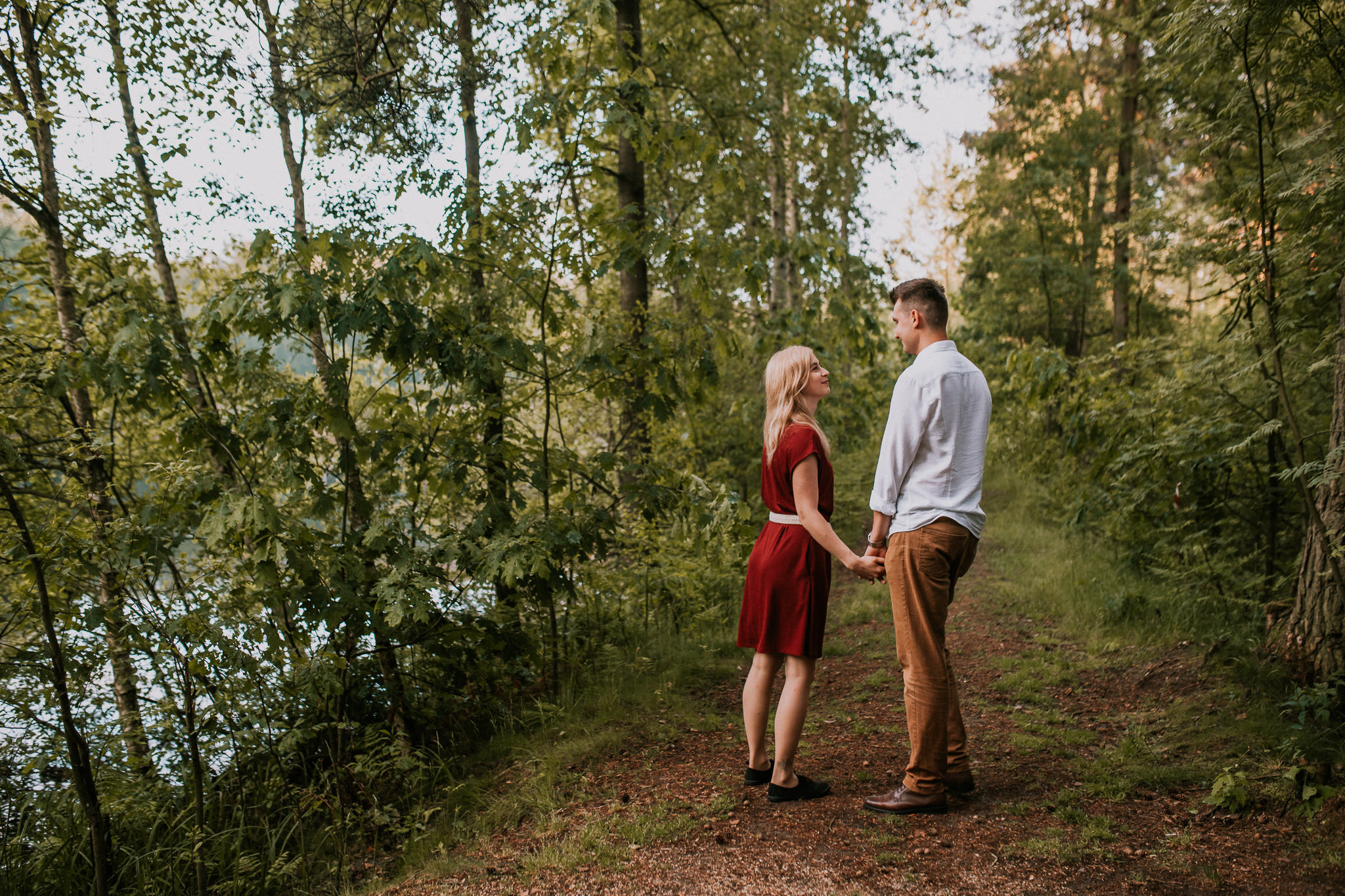 Kobieta i mężczyzna podczas spaceru rozmiawiają ze sobą, trzymają się za rękę