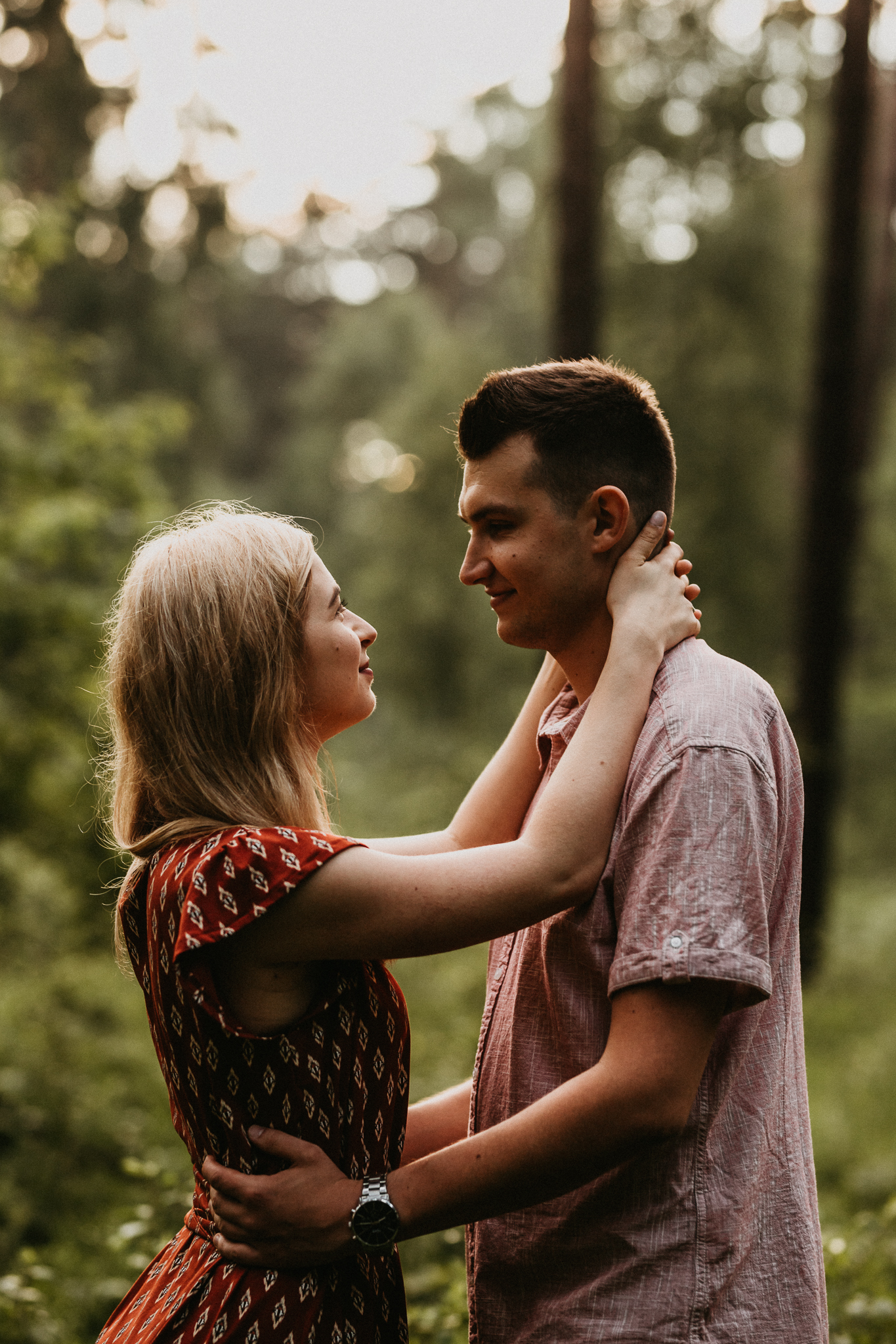 Dziewczyna trzyma za szyję chłopaka i uśmiecha się do niego