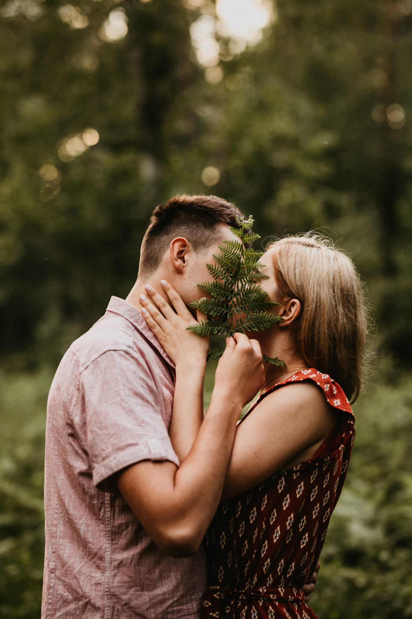 Całująca się para. Zakrywają pocałunek gałązką paproci