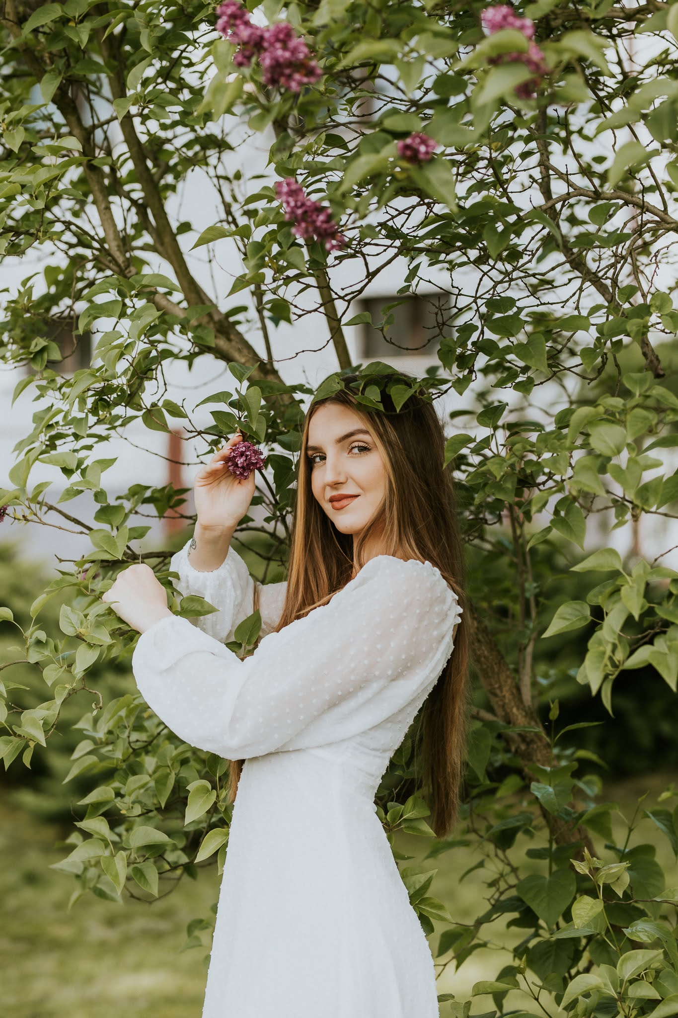 Dziewczyna trzyma się gałązki drzewa i pozuje do zdjęcia