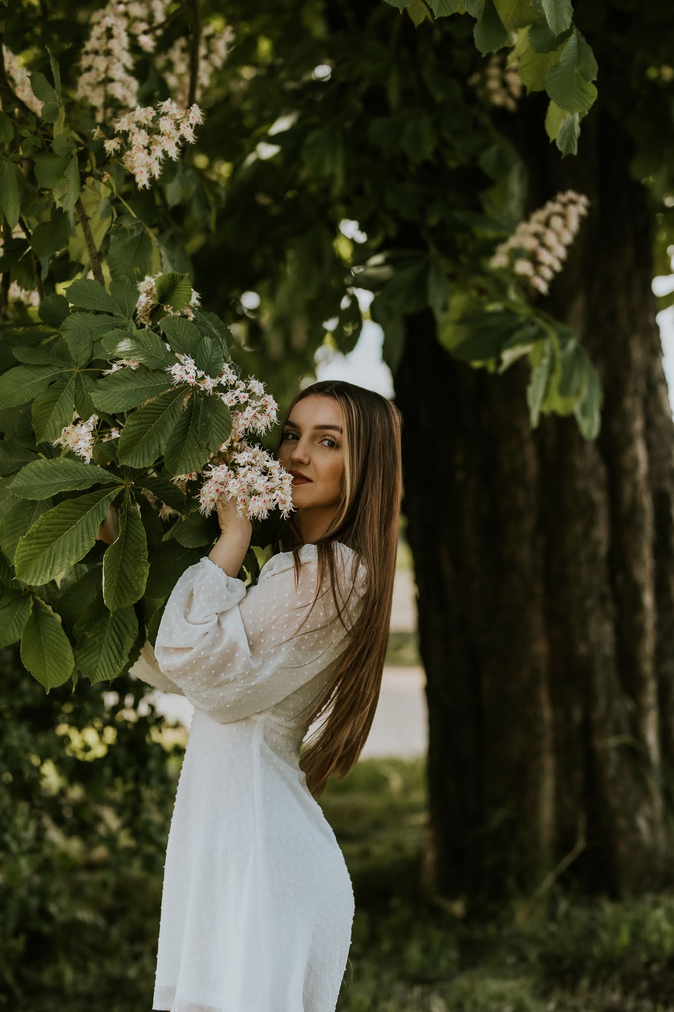 Młoda kobieta w ręku trzyma bukiet kwitnącego drzewa i wącha je
