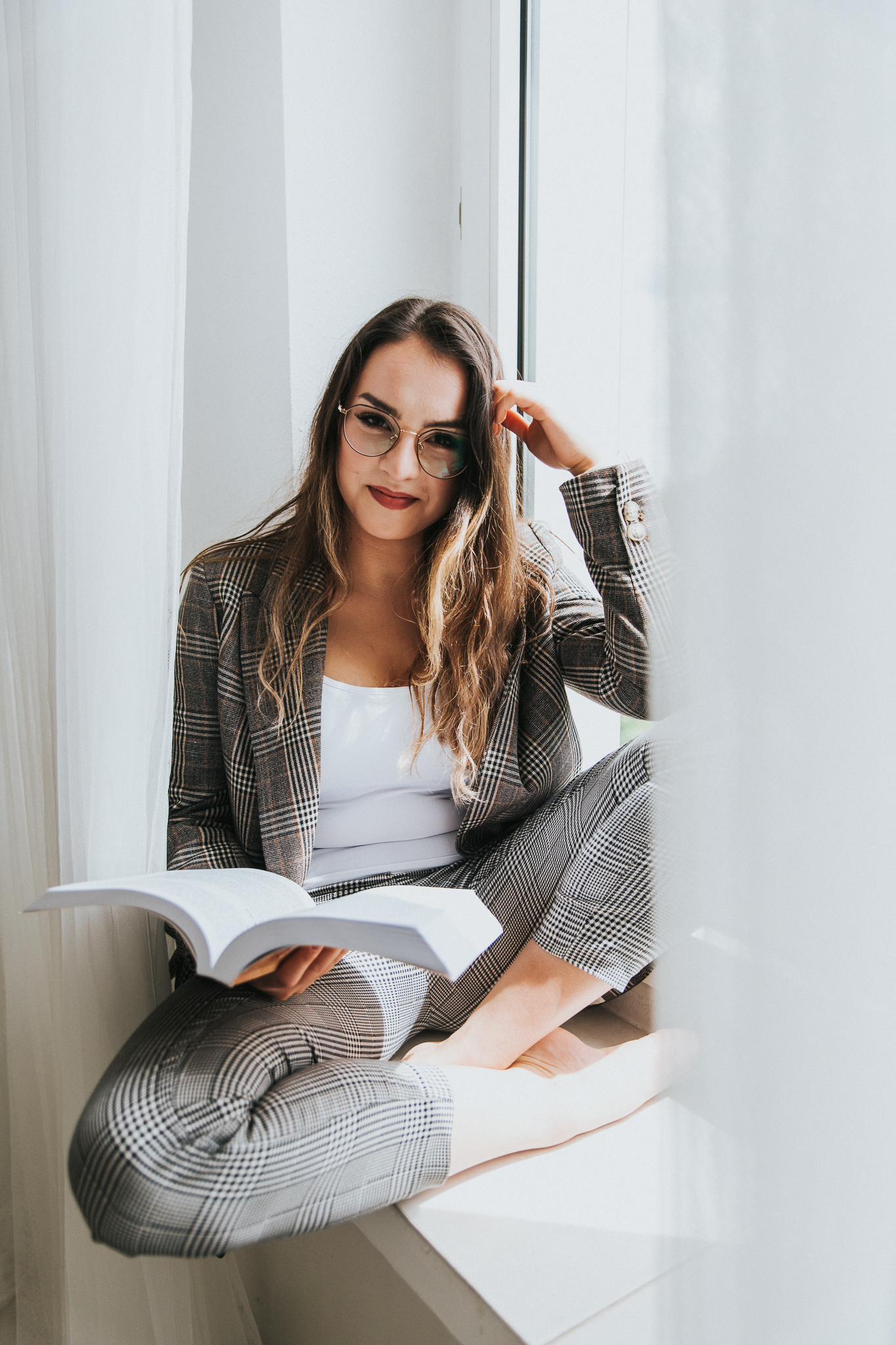 Dziewczyna siedząca na parapecie i czytająca książkę