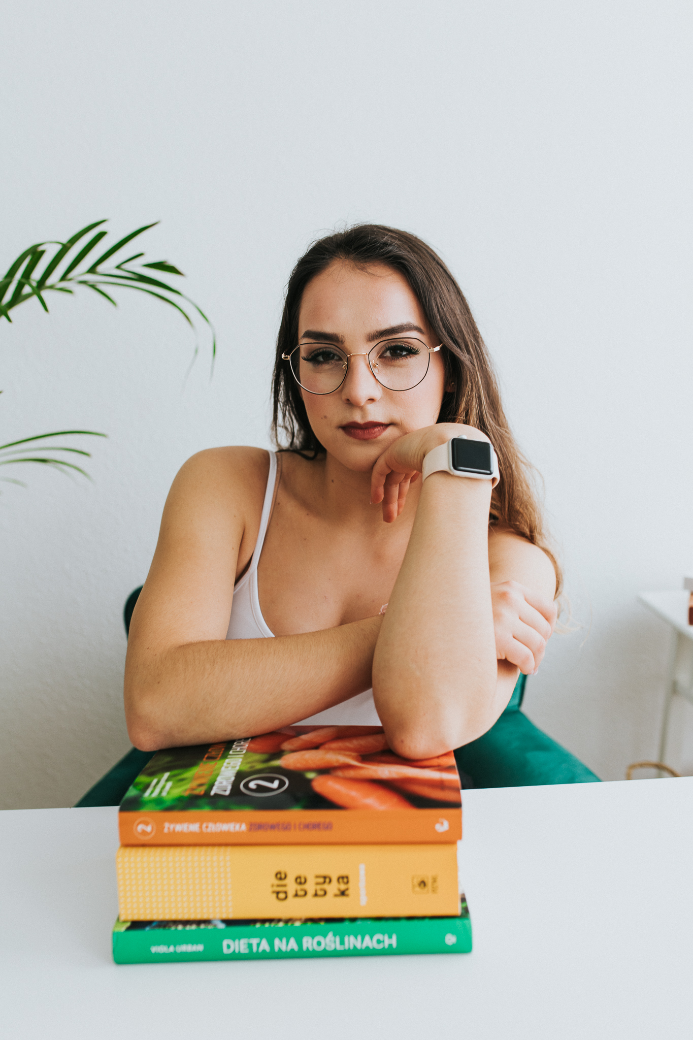 Kobieta siedząca przy stole, która ma ręce oparte na książkach