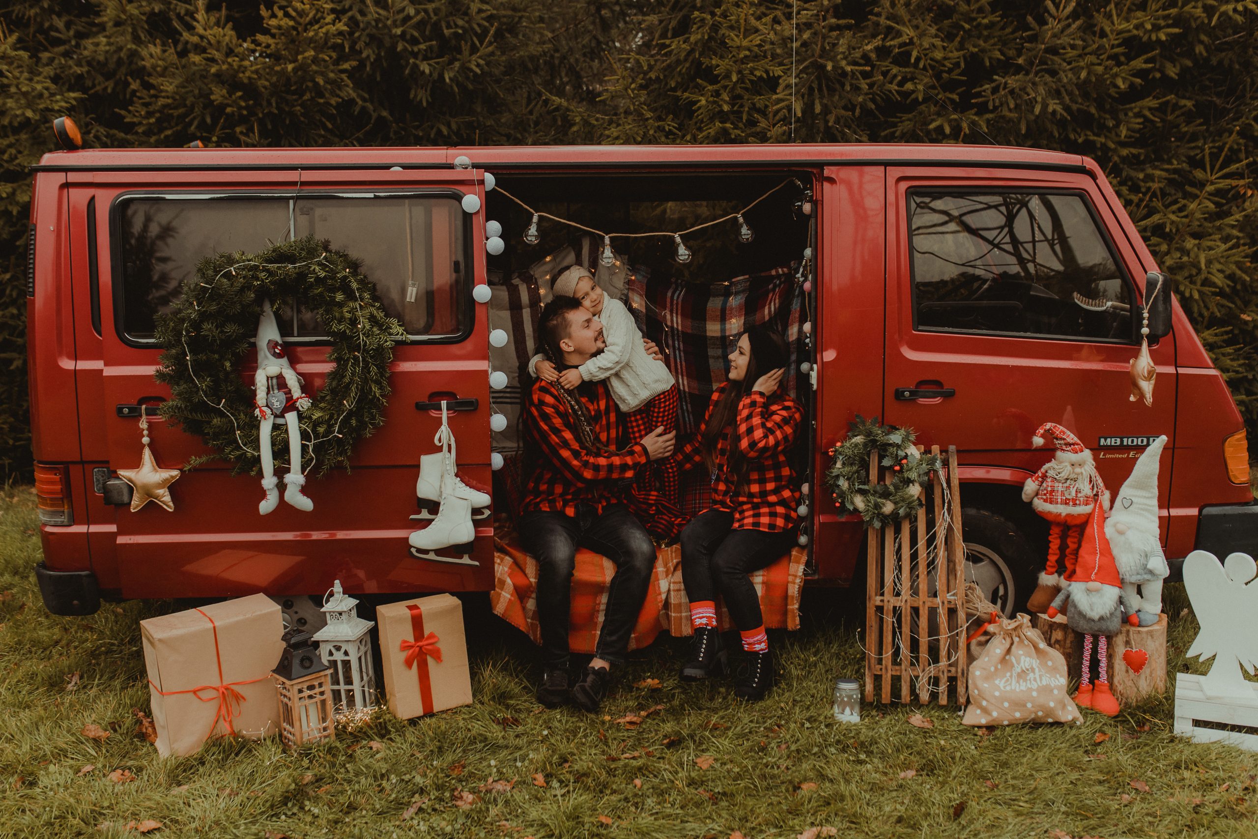 W świątecznym samochodzie dziewczynka przytula się do taty. Mama patrzy na nich z uśmiechem
