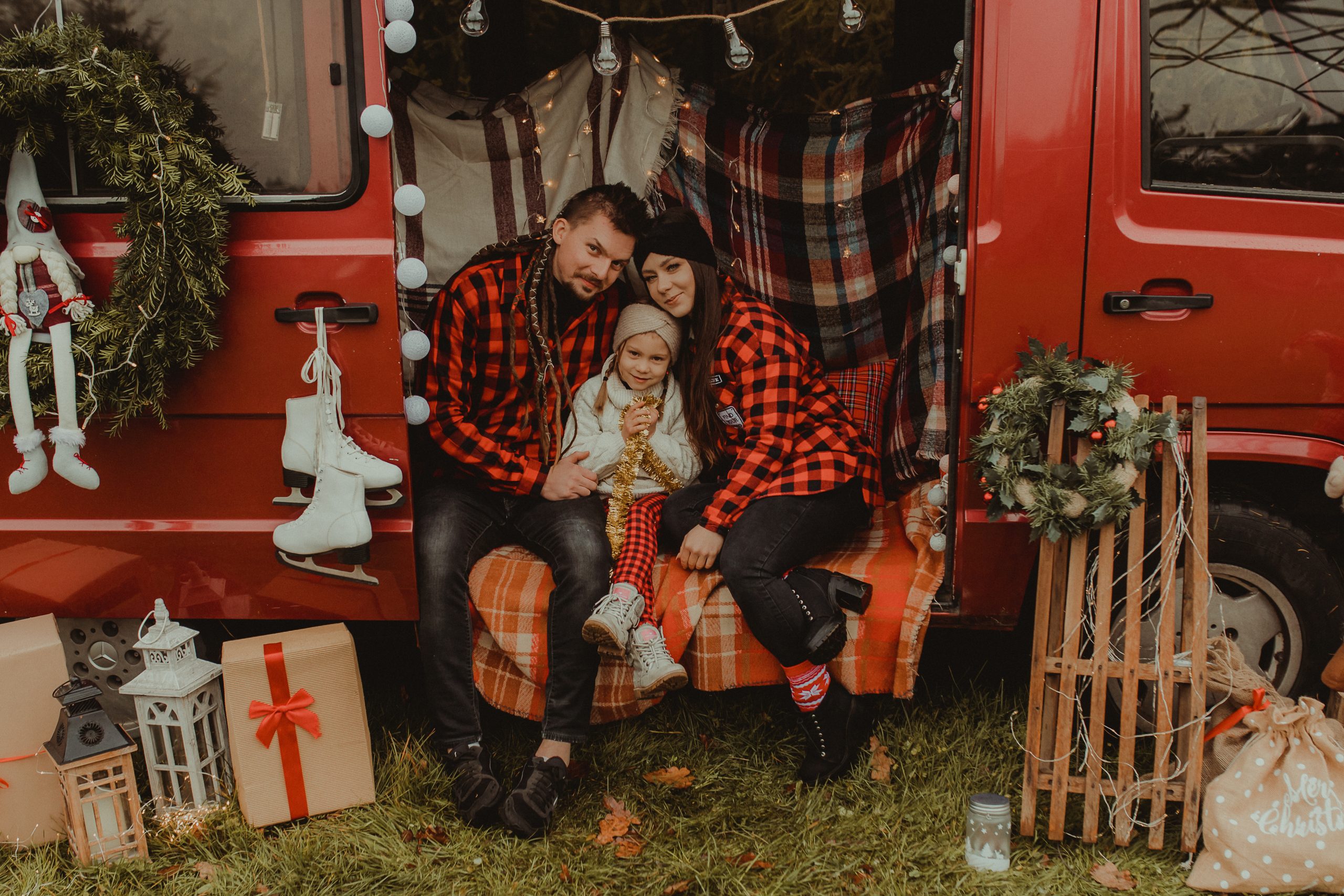 Rodzina. Mężczyzna i kobieta w flanelowej, czerwonej koszuli w kratę. Siedzą w czerwonym busie