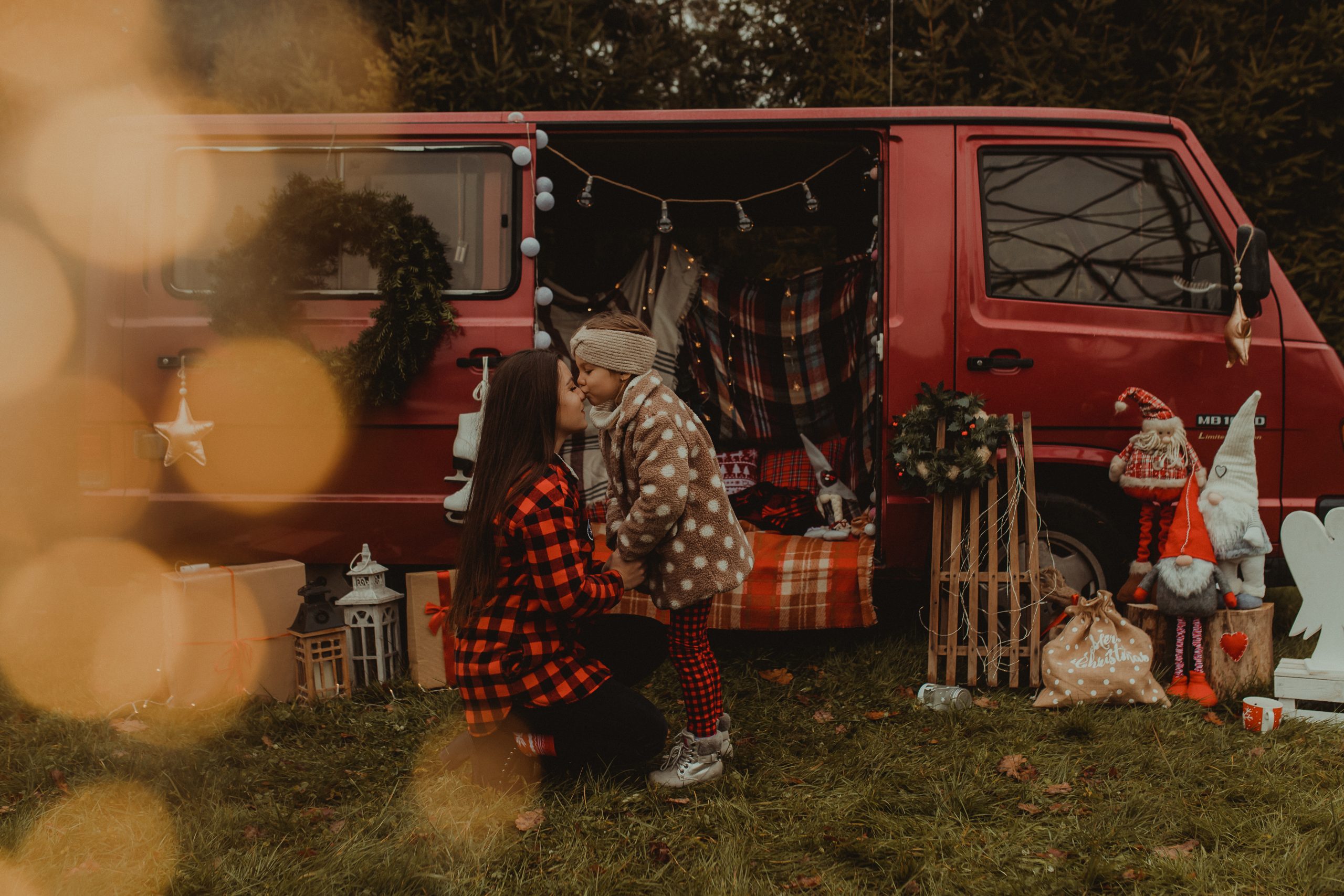 Dziewczynka całuje mamę w nos przed świątecznym busem