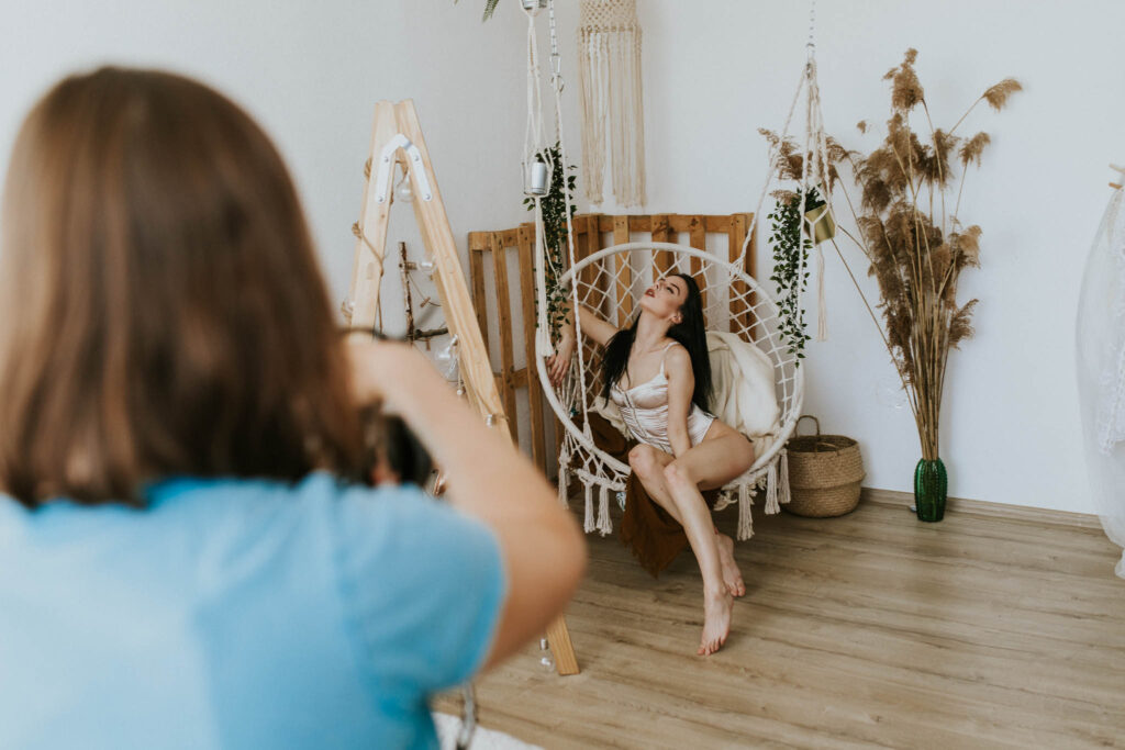 Kobieta robi zdjęcia modelce na huśtawce boho. Warsztaty sesji kobiecej