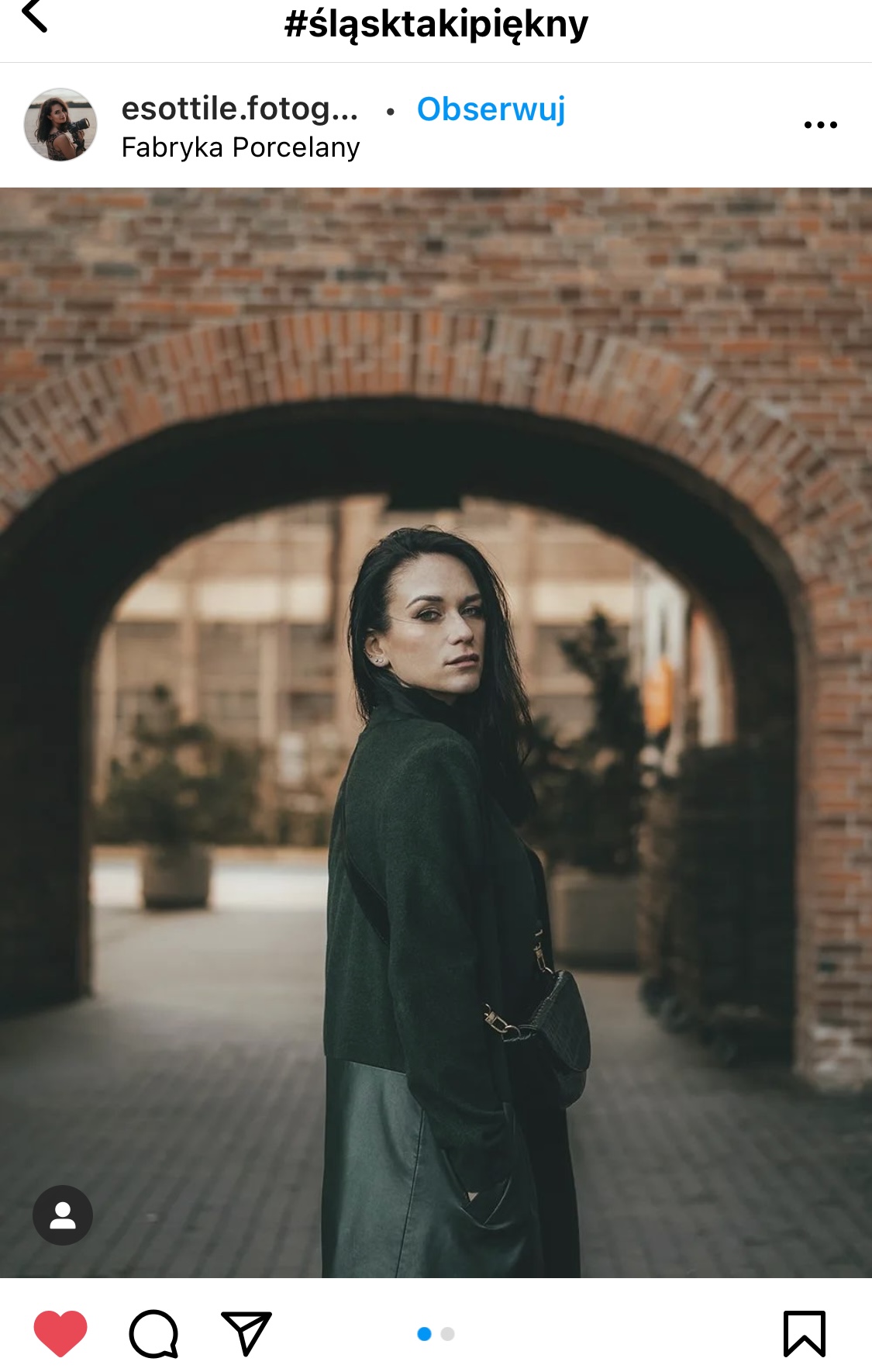 Kobieta stojąca w ceglastym przejściu, patrzy w stronę obiektywu.