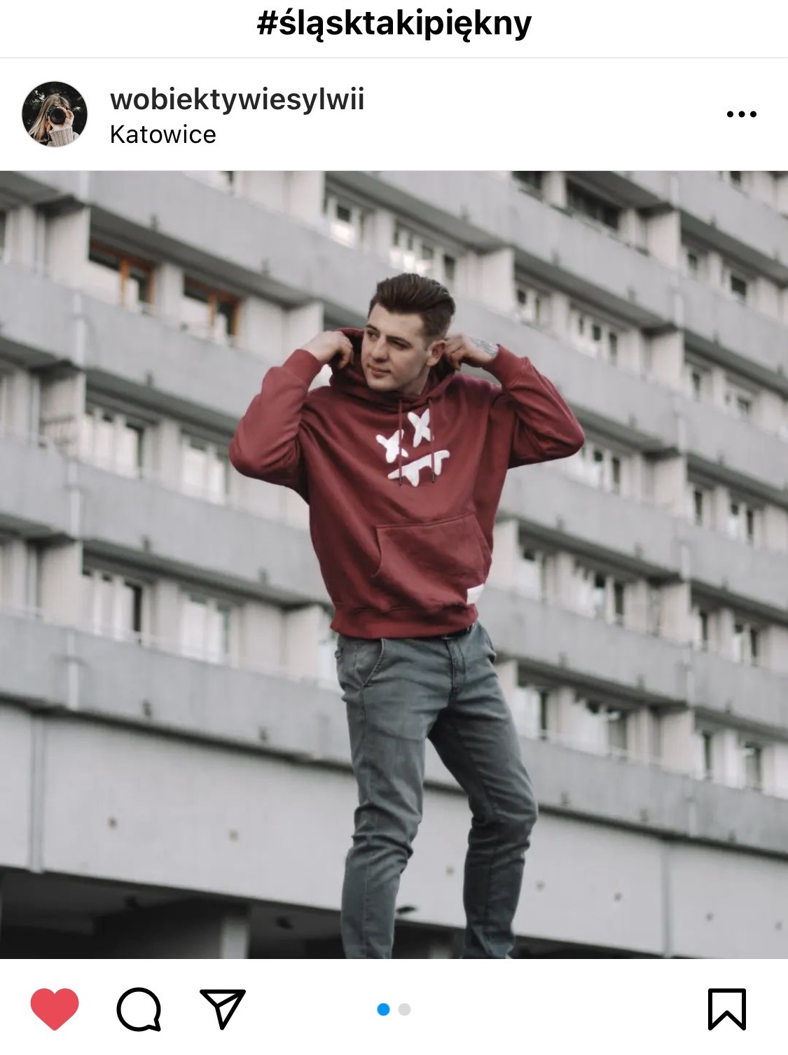 Mężczyzna w bluzie na tle bloku z wielkiej płyty