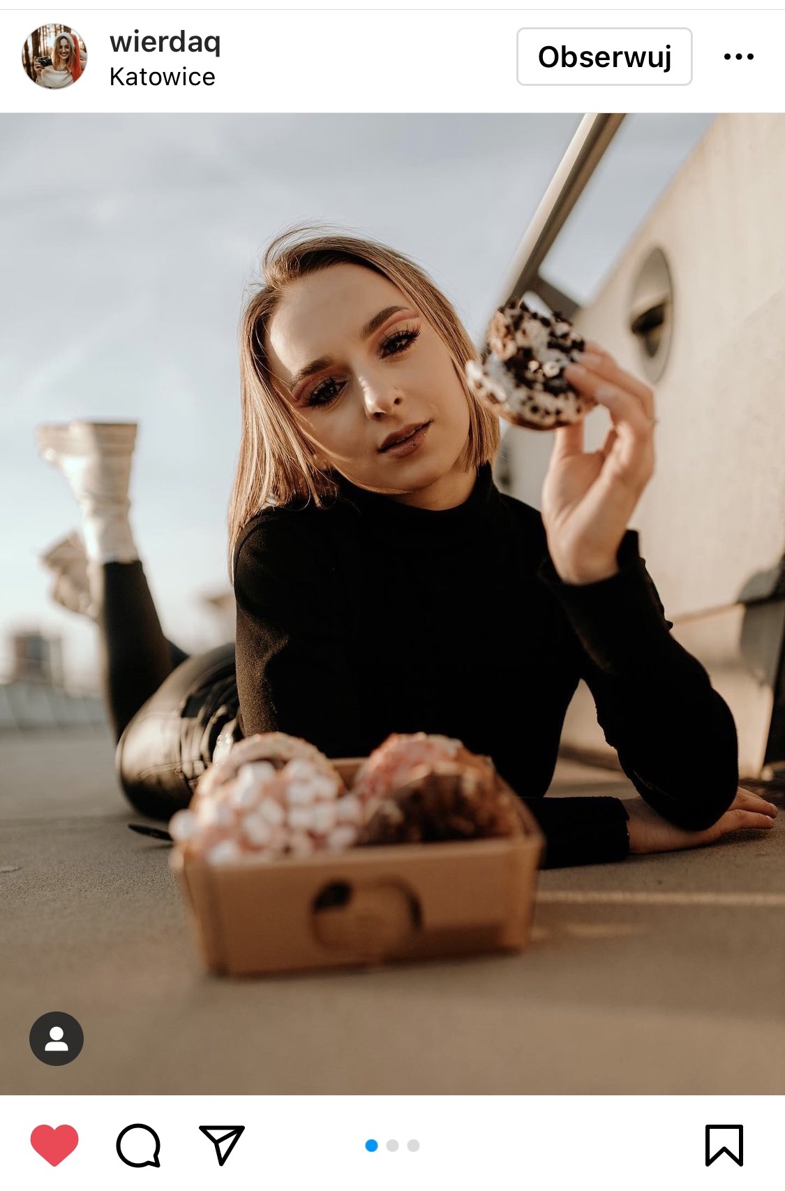 Dziewczyna leżąca na betonie w ręce trzyma donut