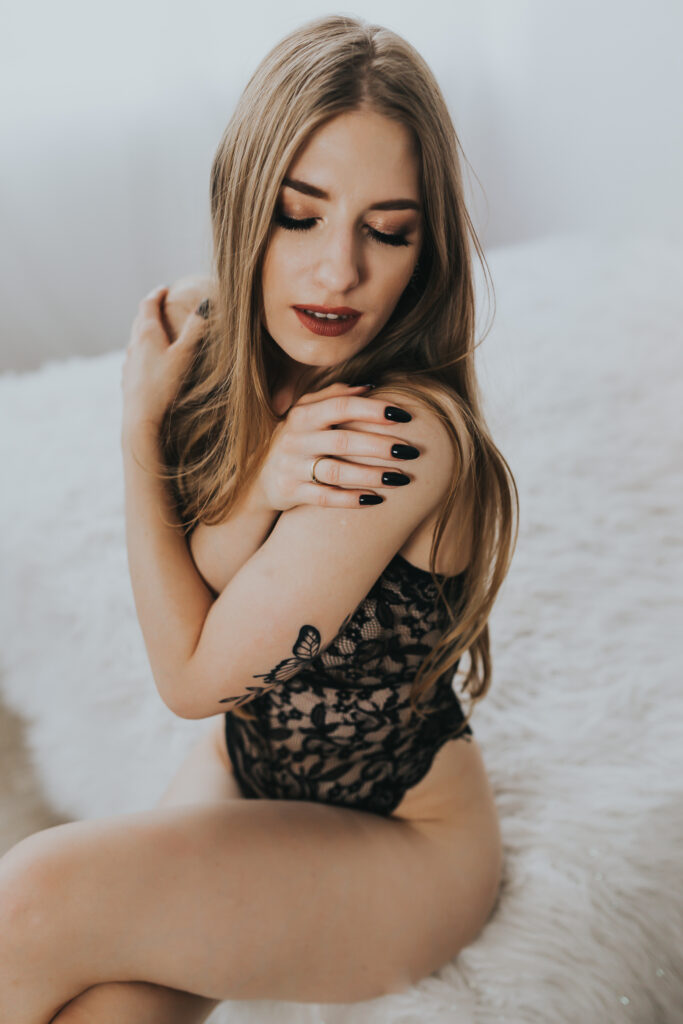 kobieta siedząca na krawędzi łóżka i ręce ma skrzyżowane na ramionach