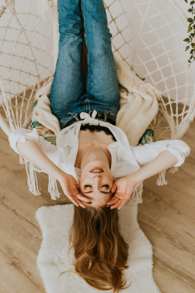 dziewczyna leży na huśtawce i trzyma się skroni, do góry nogami