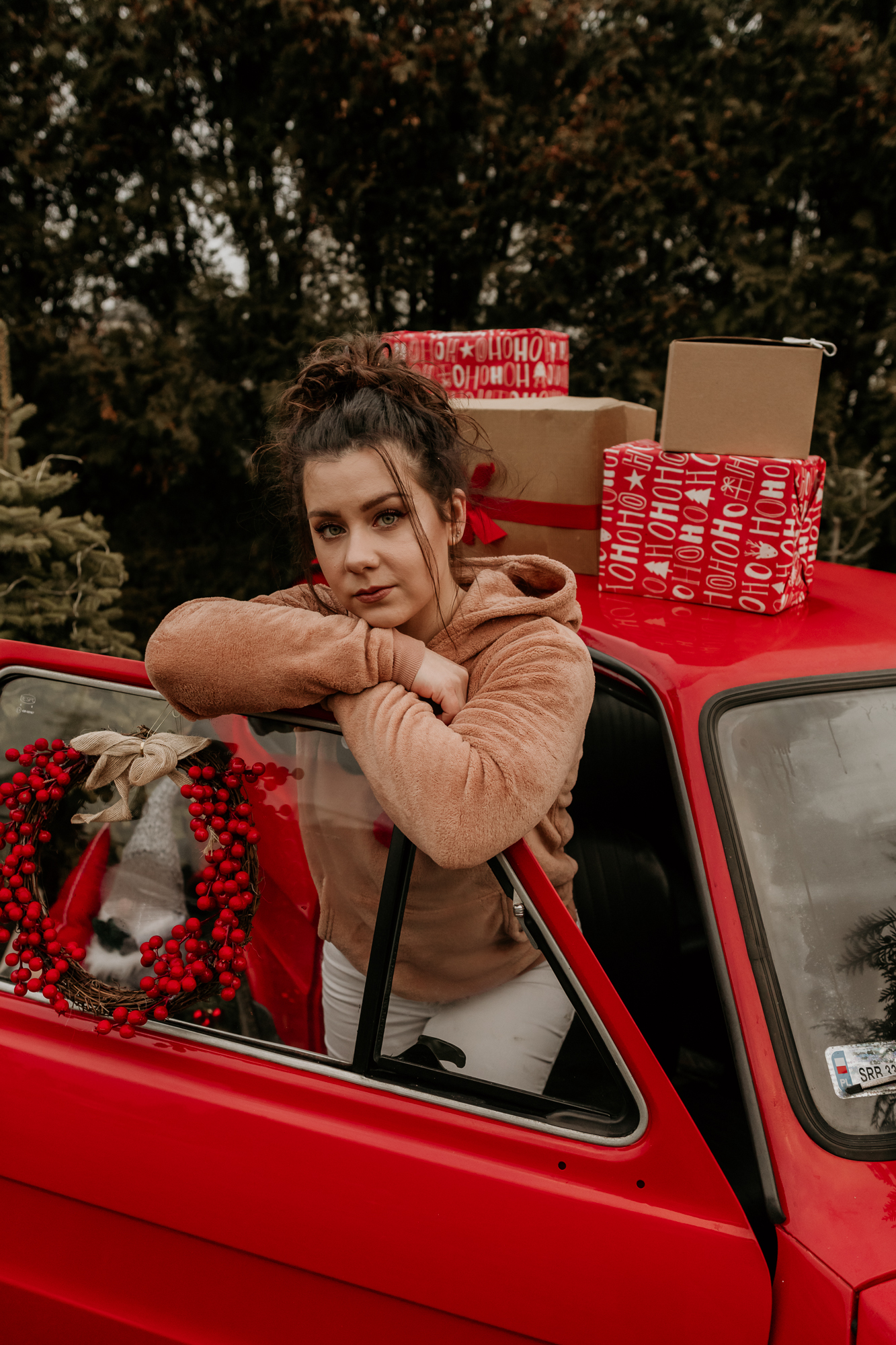 kobieta oparta o drzwi samochodu z prezentami na dachu