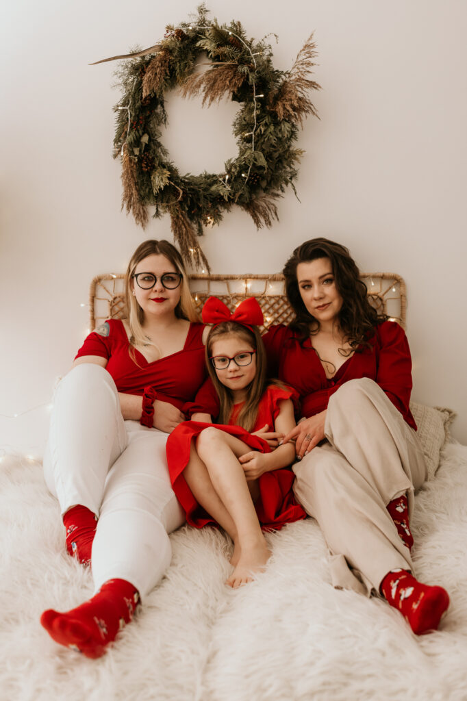 świąteczny portret dwóch kobiet i dziewczynki na środku, siedzą na łóżku