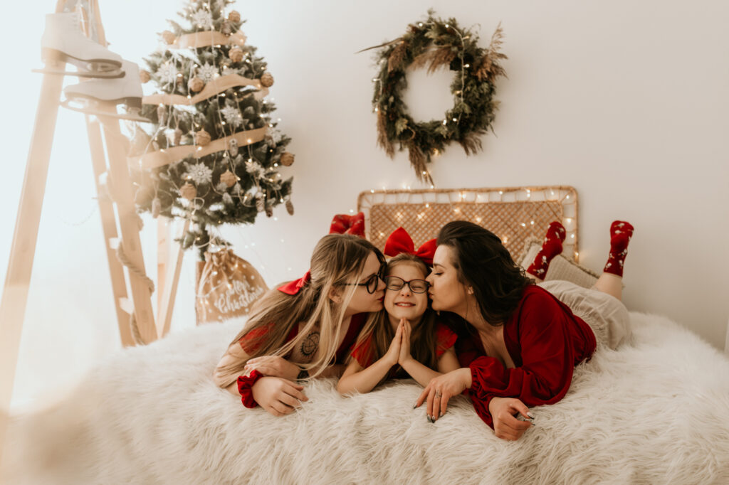 dwie kobiety i dziewczynka w czerwonym leżą na łóżku