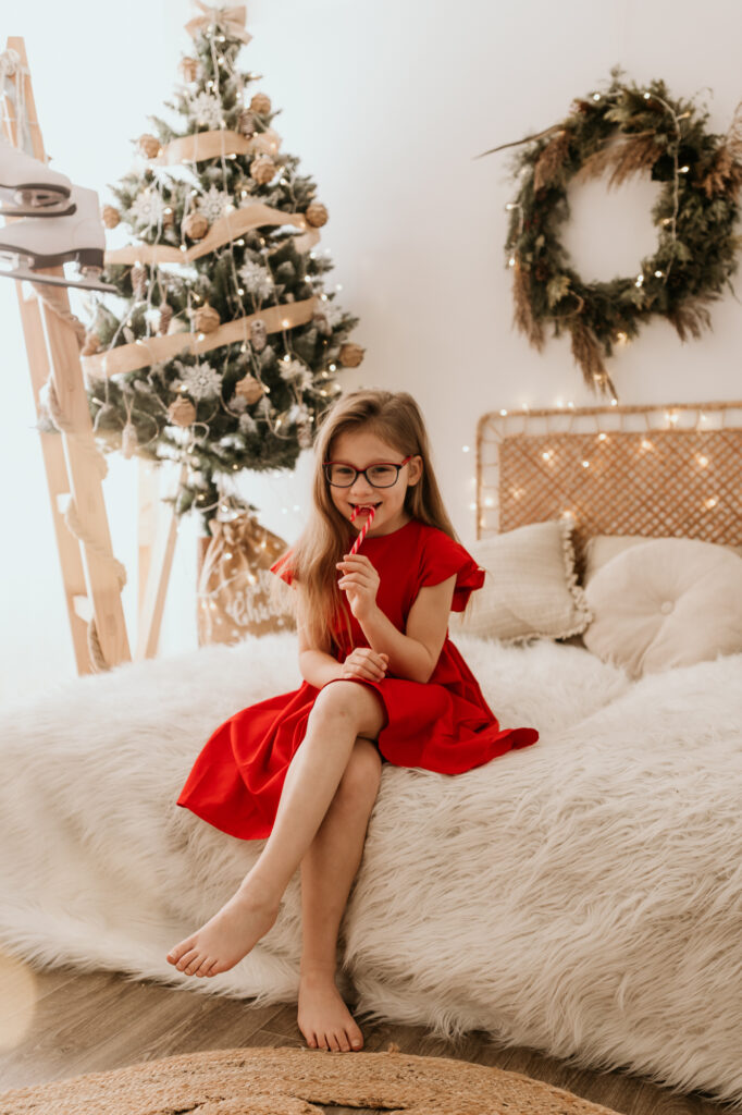 dziewczynka siedzi na łóżku z świątecznym lizakiem