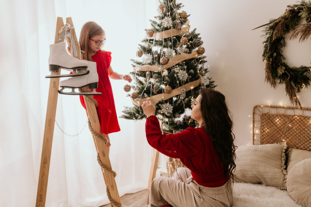 kobieta ubiera choinkę a dziewczynka stoi na drabinie