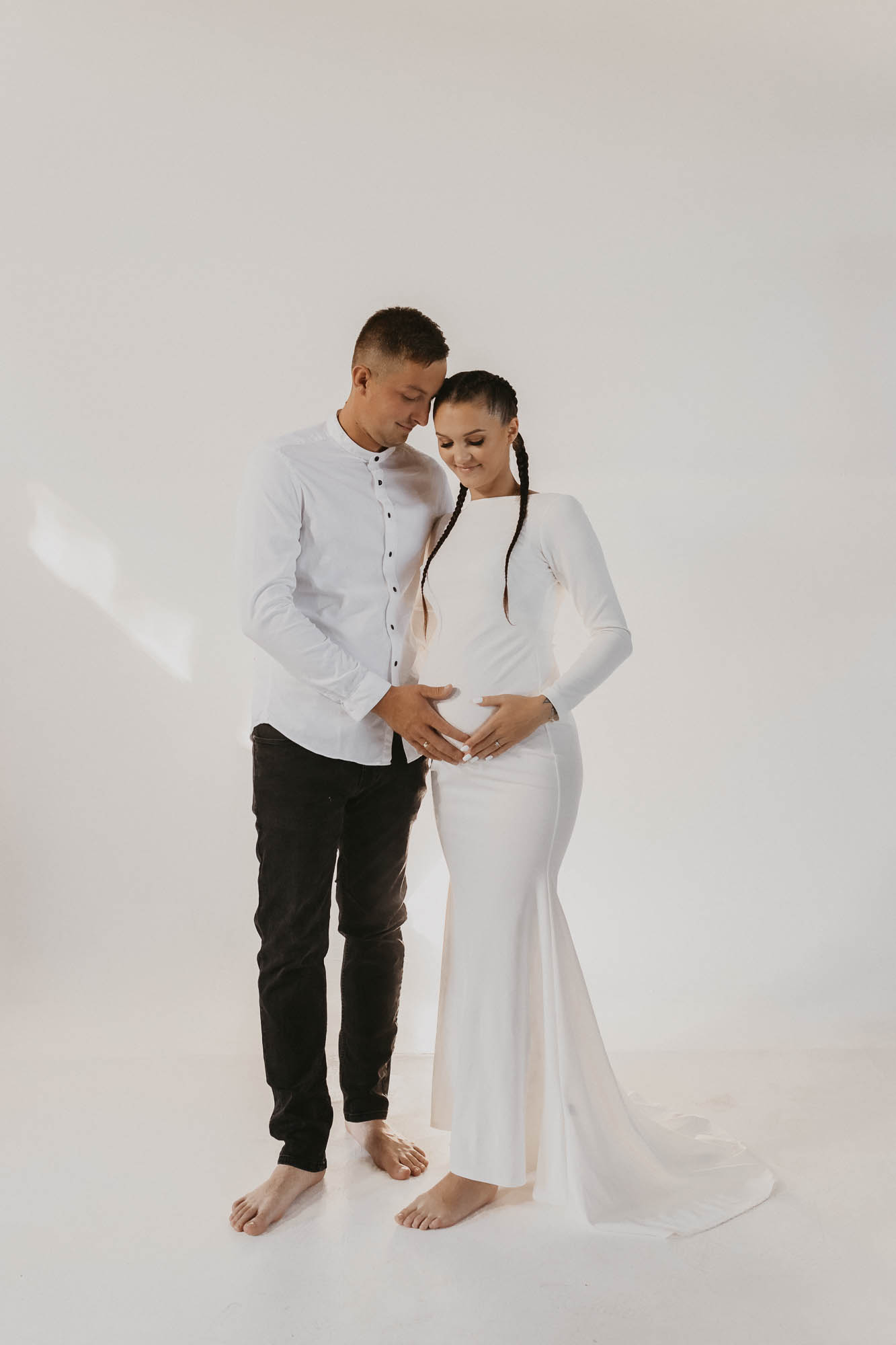 partnerzy w bieli przytulający się sesja ciążowa