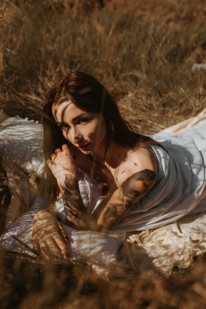 kobieta leży w trawie i spogląda się w obiektyw ma na sobie kołdrę