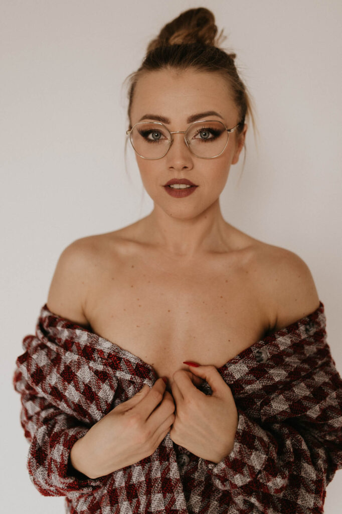 kobieta na zdjęciu ma odkryte ramiona i ubrna jest w koszulę w kratę