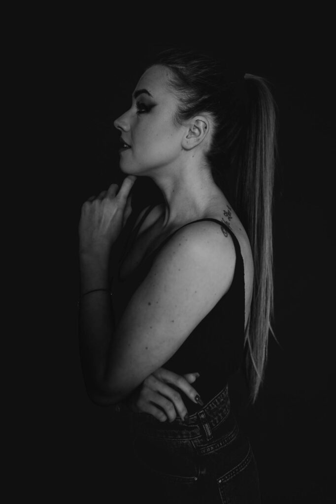 kobieta odwrócona bokiem do obiektywu trzyma rękę na brodzie