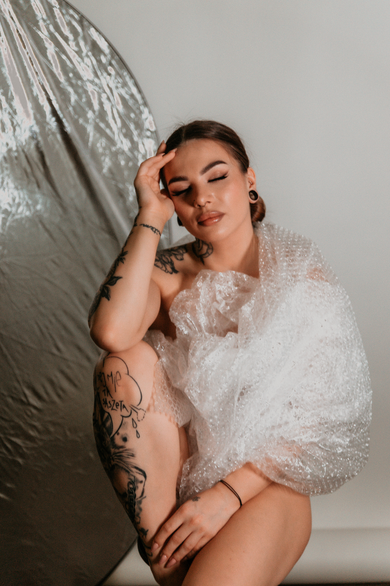 kobieta siedzi i jest owinięta w folię, ma zamknięte oczy